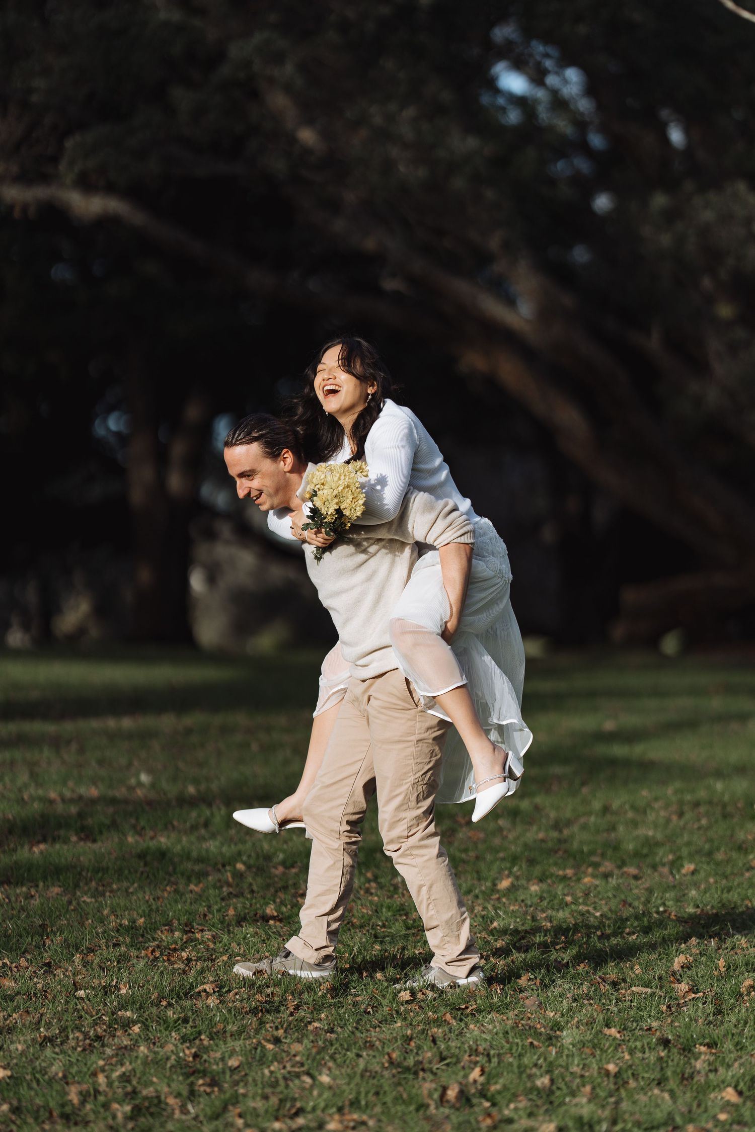 A couple engages in playful piggyback rides during their outdoor photoshoot.
