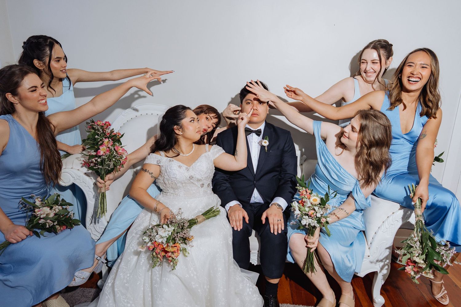 Wedding party in light blue dresses posing playfully for group photos.