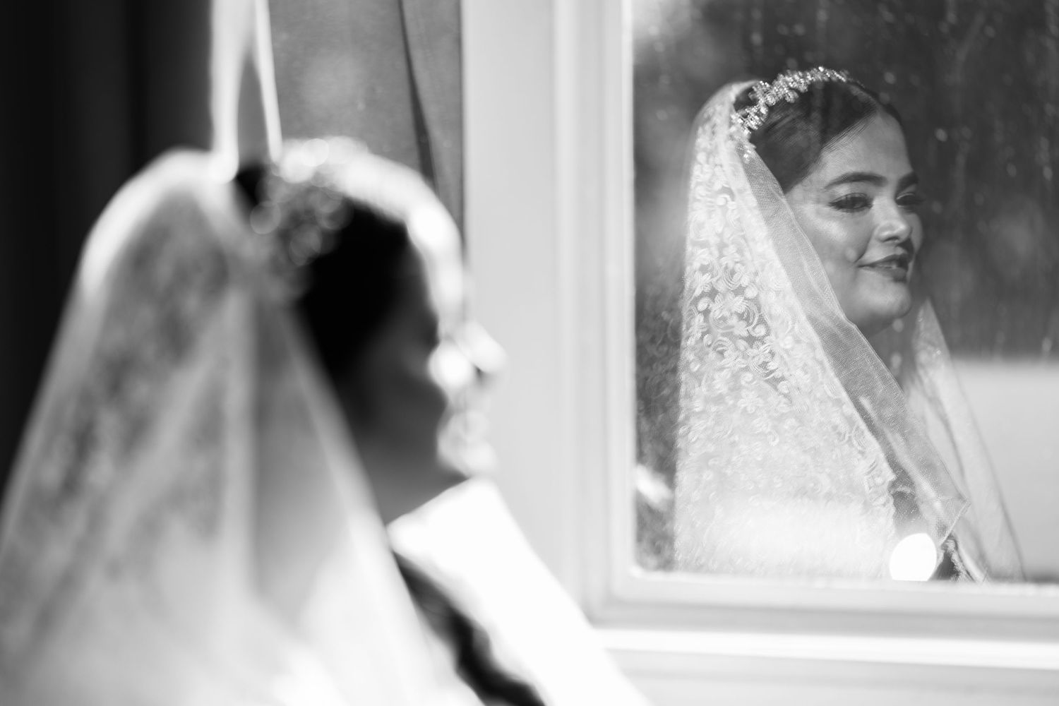 Artistic black and white wedding photography through window reflections.