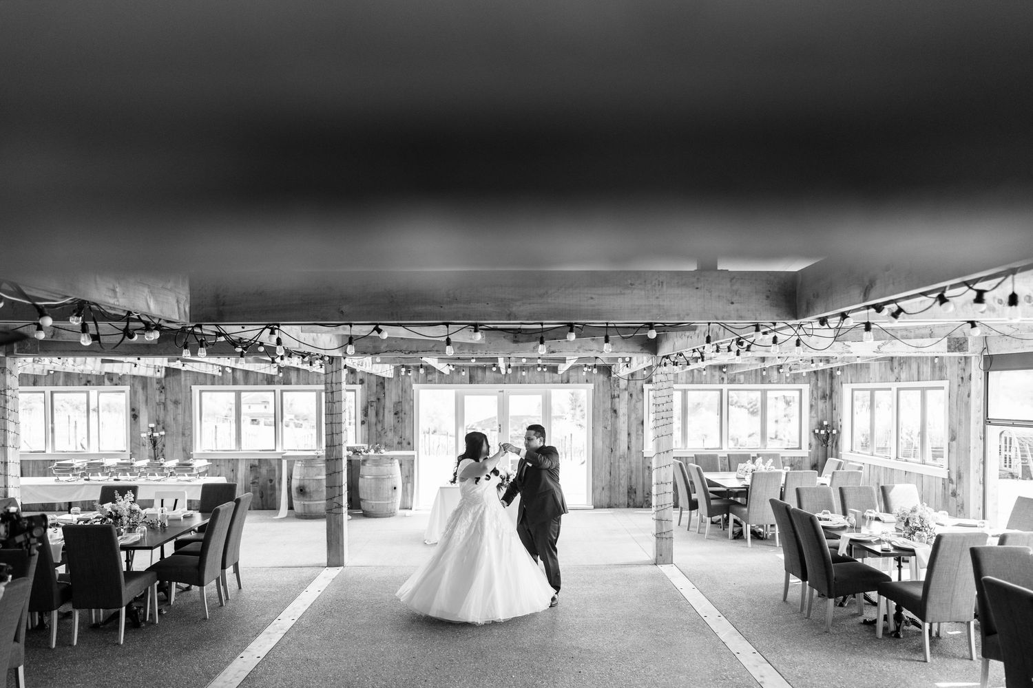 Interior view of an elegant wedding reception venue with white tables and chairs.