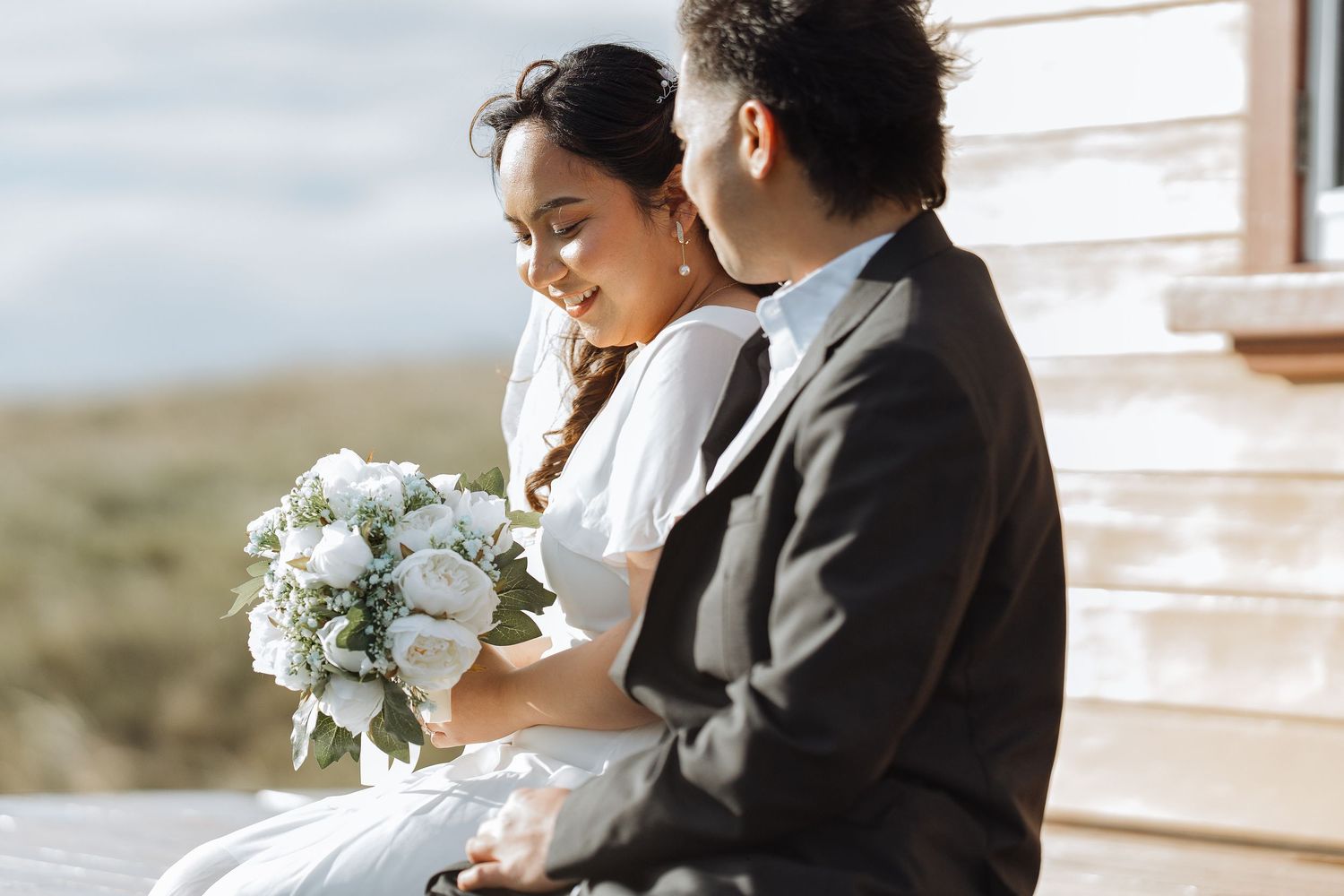 A romantic moment captured on a wooden deck overlooking the ocean.