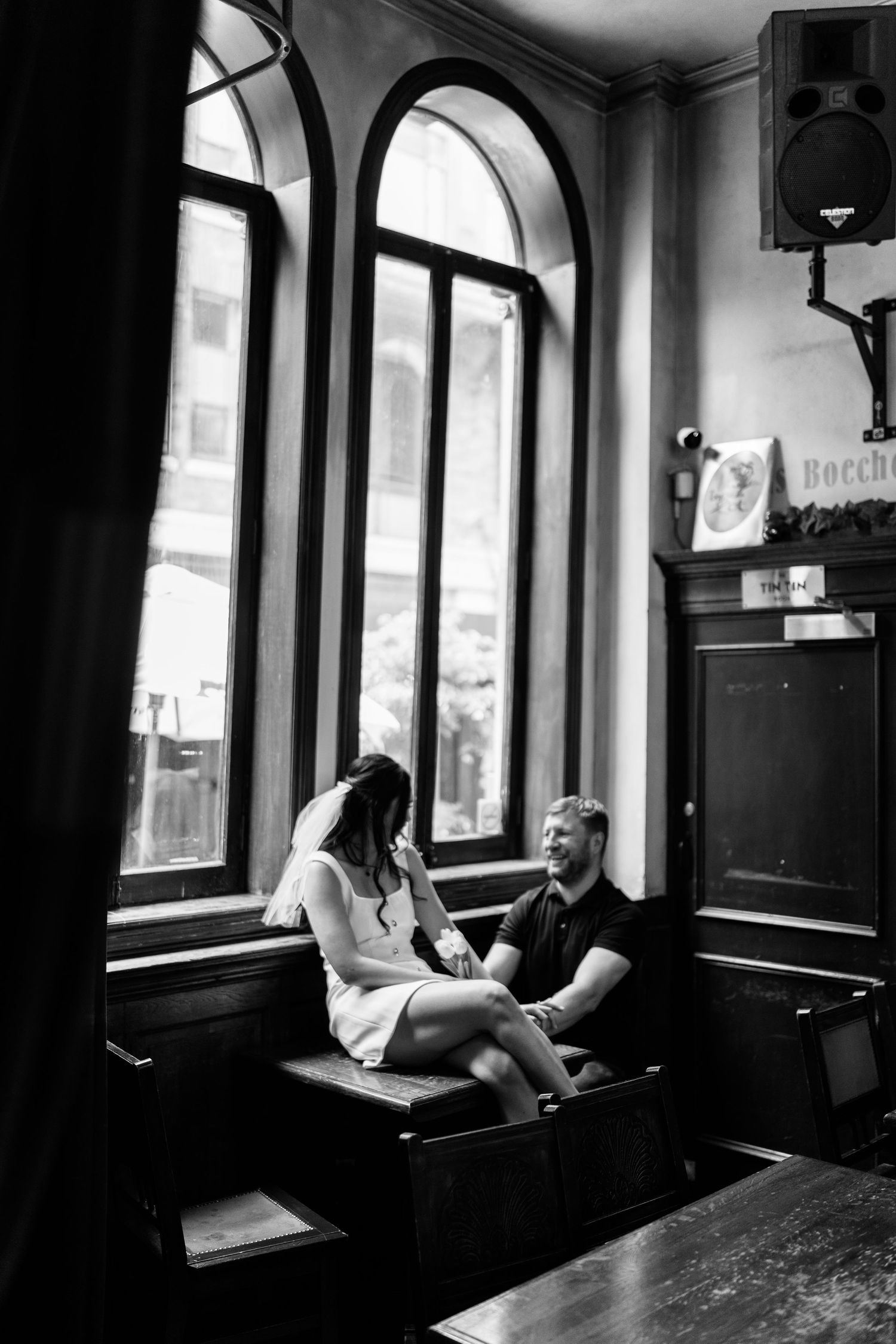 A couple sits together in a vintage cafe with arched windows.