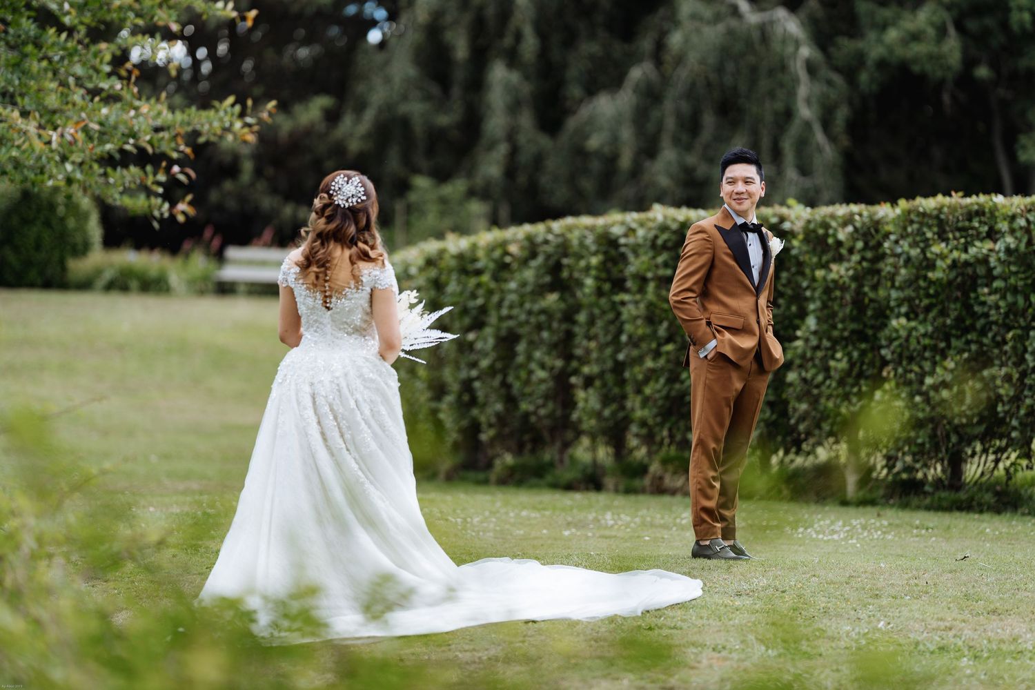 Wedding couple walking through a lush garden setting with flowing white dress.