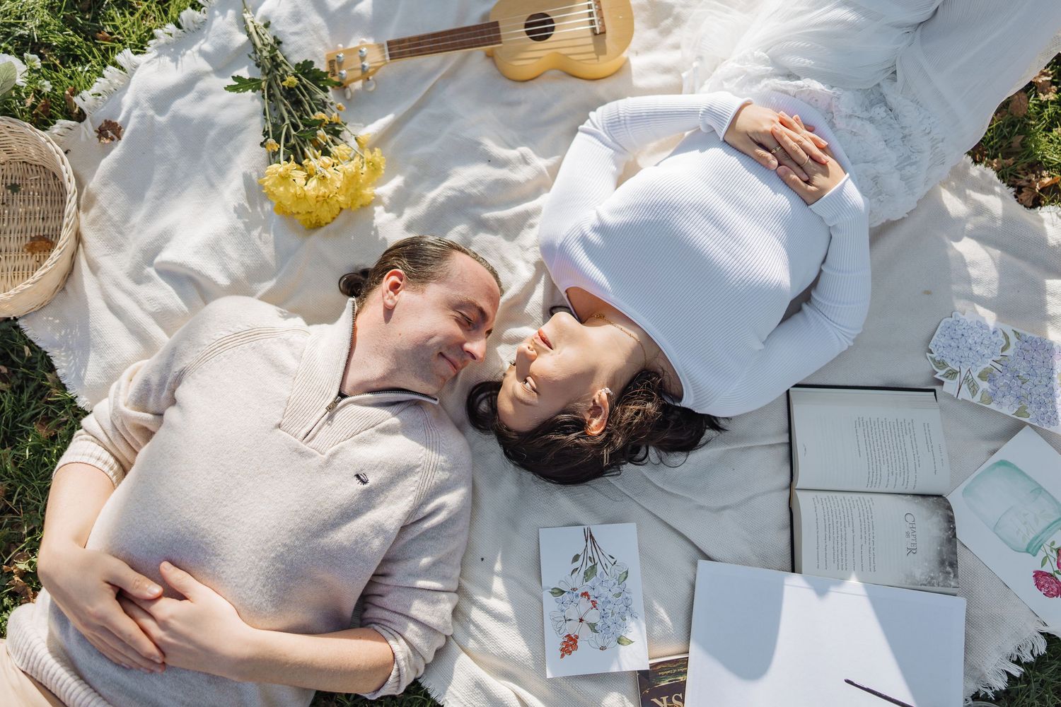 A sunny outdoor picnic scene with a guitar and yellow flowers on a white blanket.