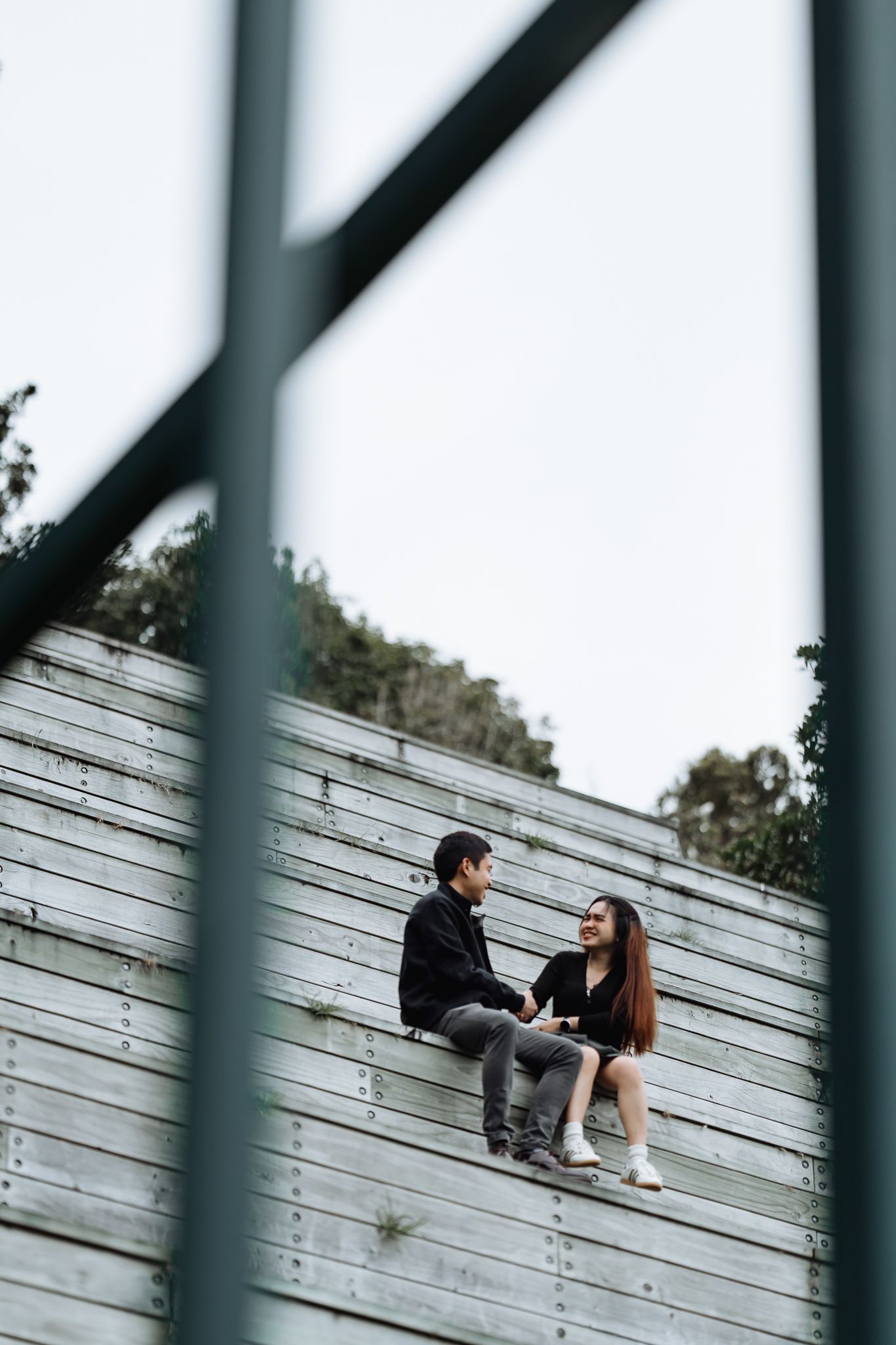 A couple sits together on white wooden steps having a conversation.
