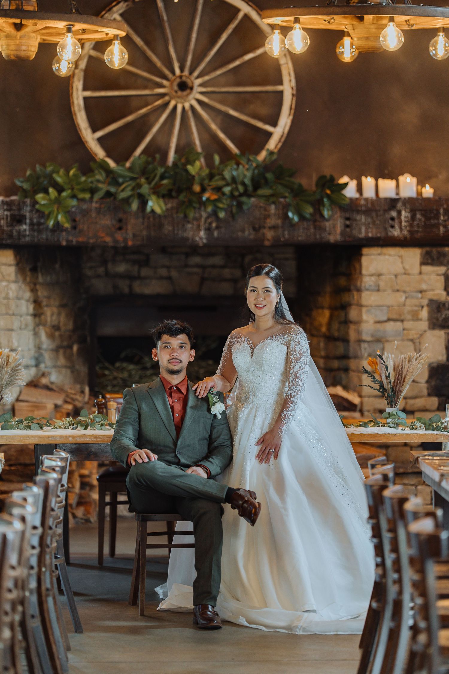 Rustic wedding venue interior featuring wagon wheel decor, stone walls, and romantic lighting.
