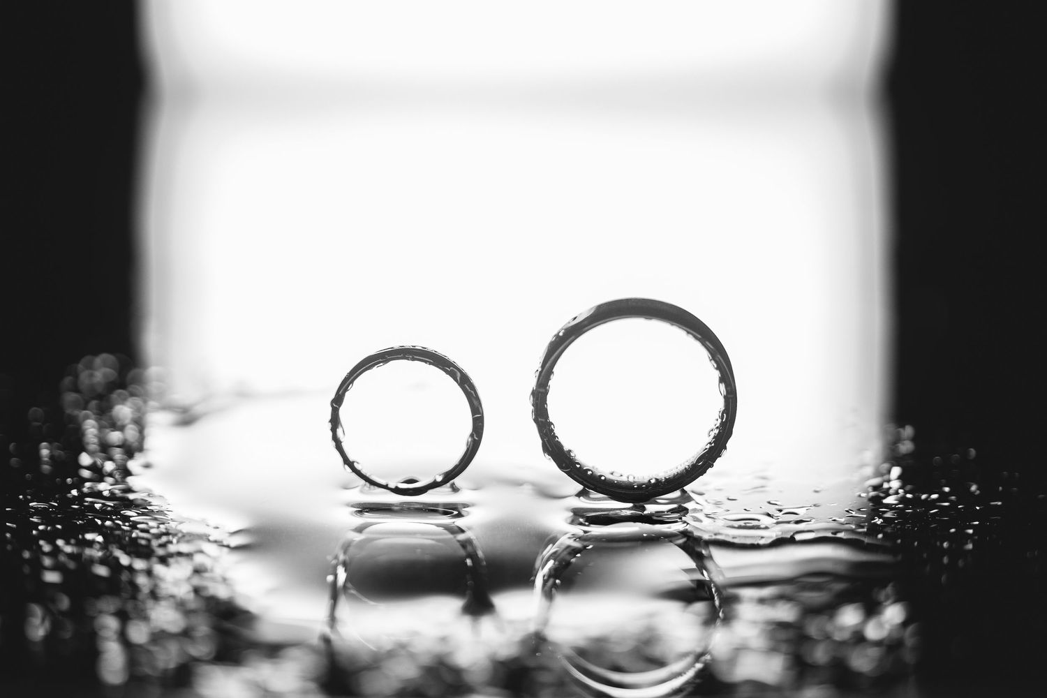 Artistic black and white macro shot of wedding rings with dramatic lighting.