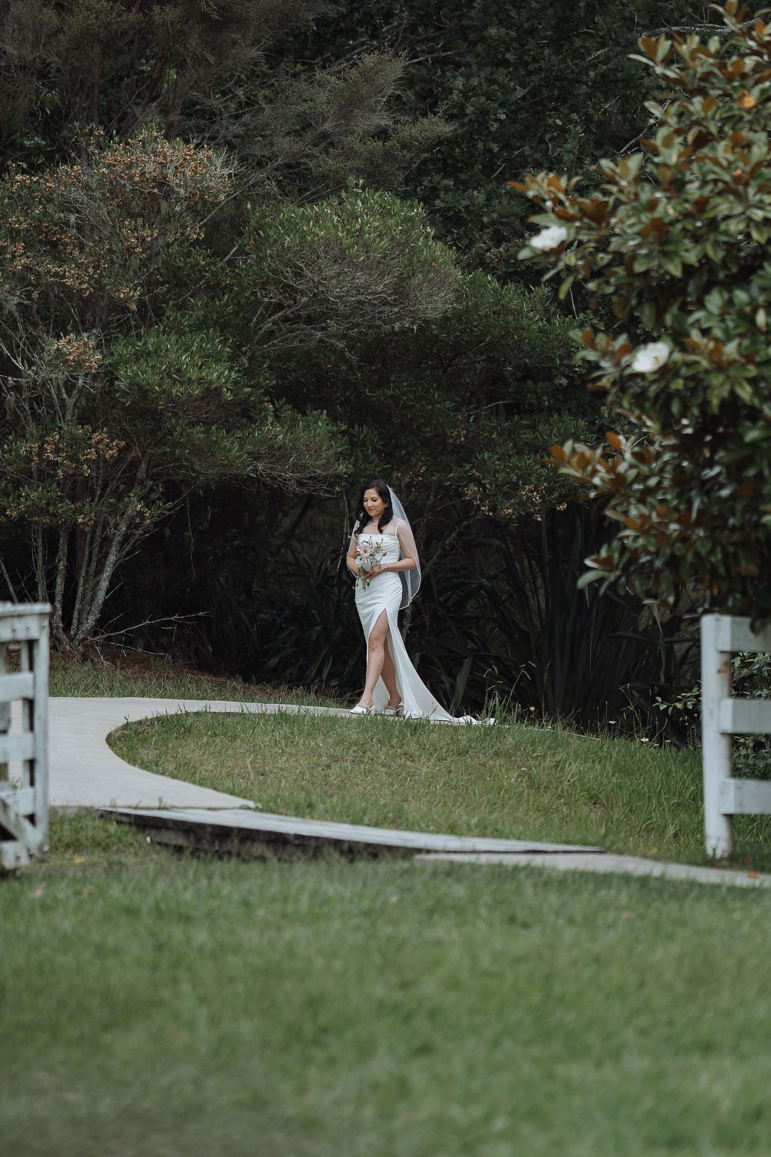 A white-fenced pathway through lush greenery creates a romantic outdoor setting.