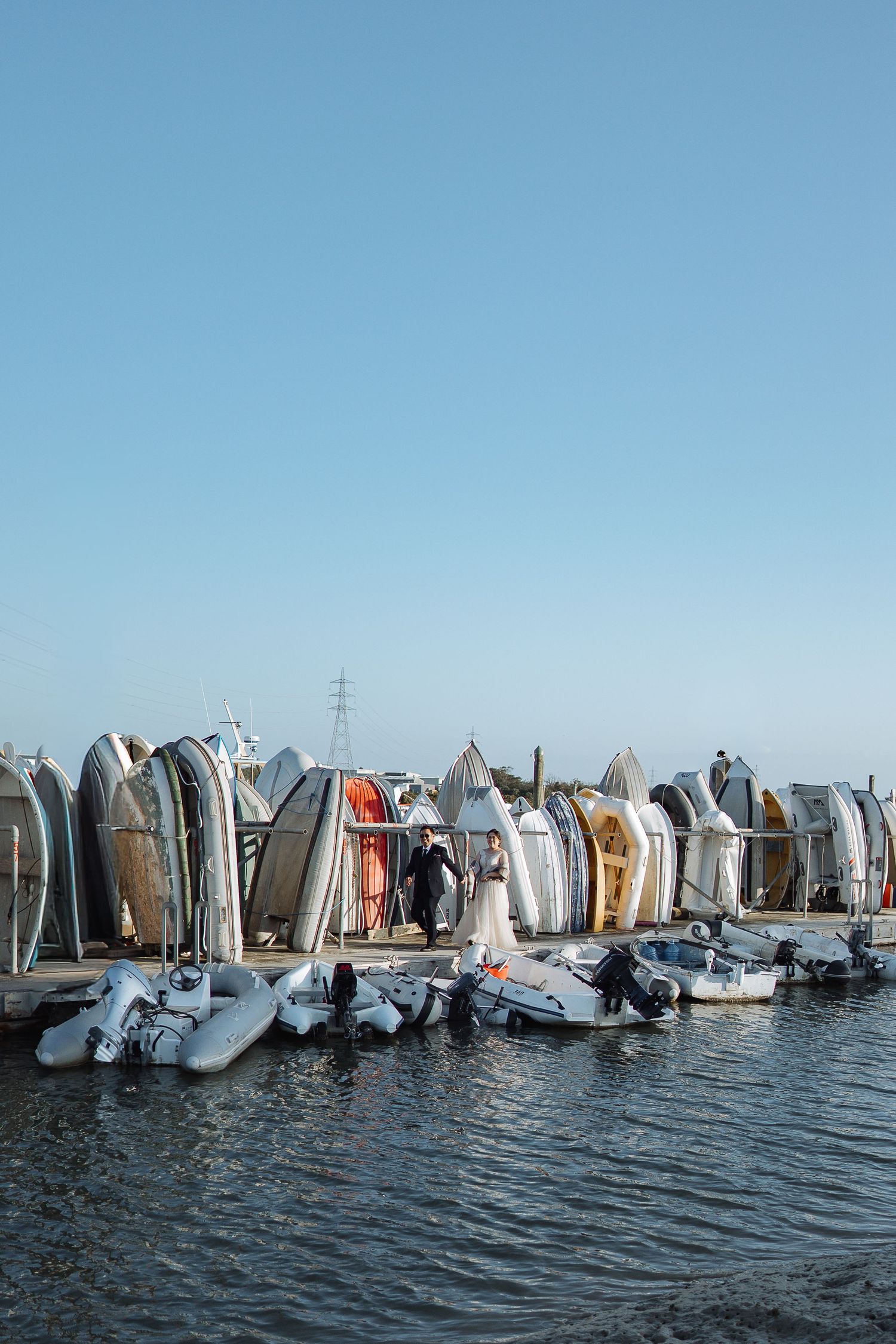 A collection of surfboards lined up along the shoreline against a bright blue sky.