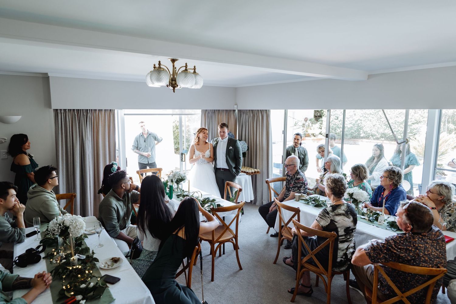 Panoramic view of wedding guests seated in a modern white reception room.