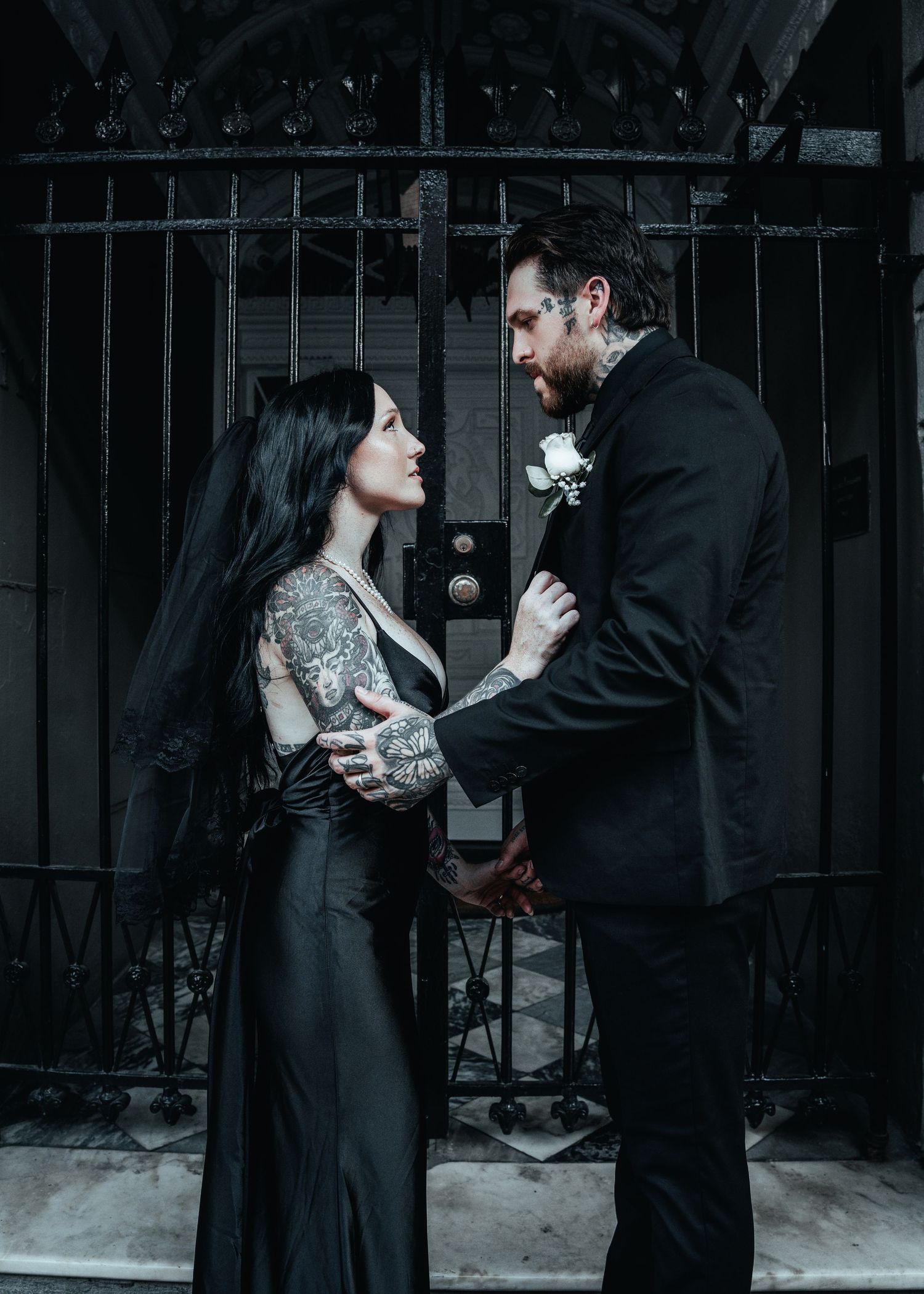 A romantic couple in black attire share intimate moments against an iron gate background in a series of artistic photos.