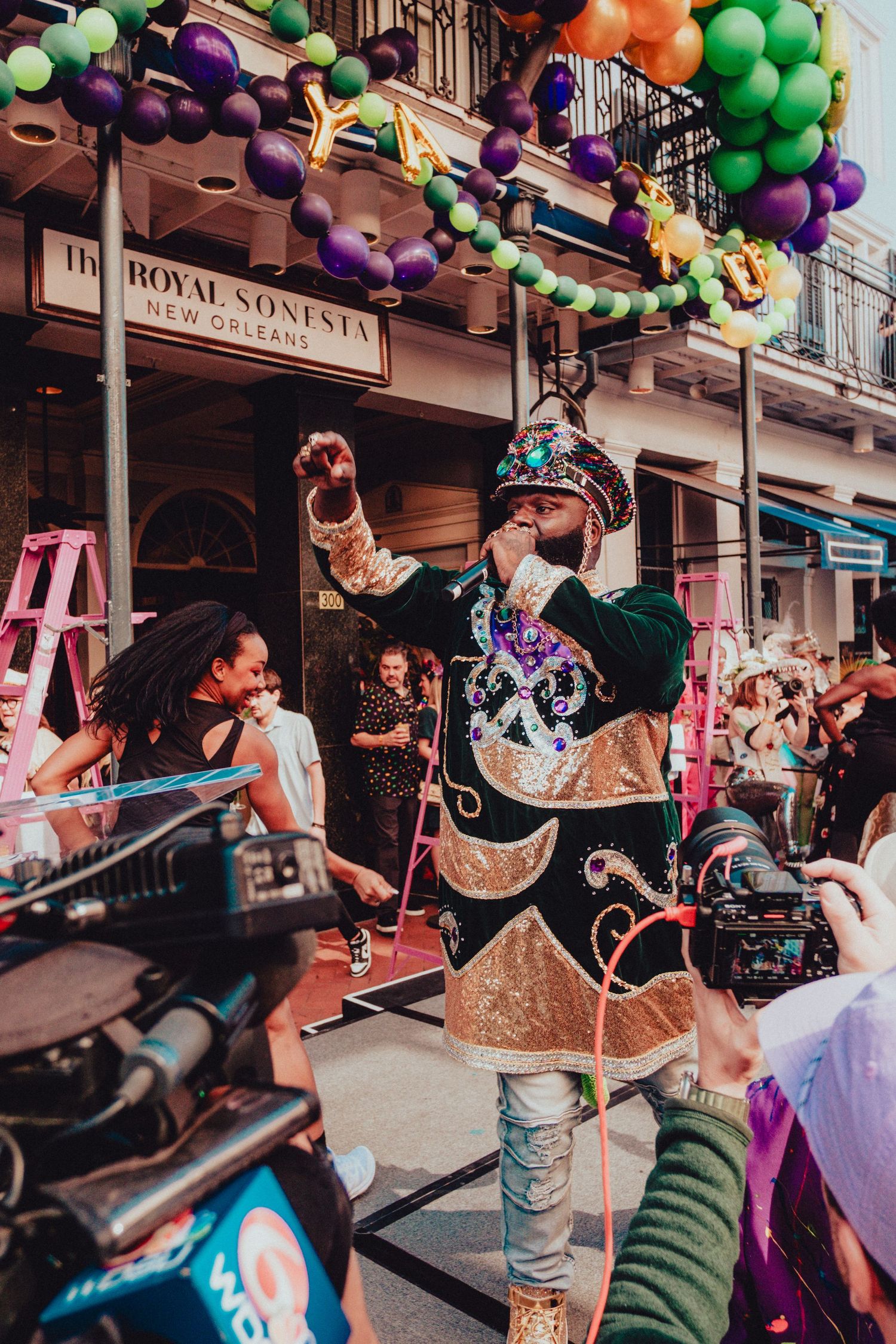Costumed performer entertaining crowd outside Royal Sonesta during Mardi Gras festivities.