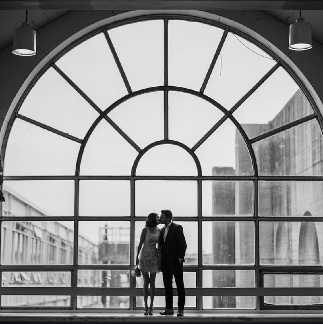 Silhouettes against a large arched window showcase an architectural interior space with dramatic lighting.