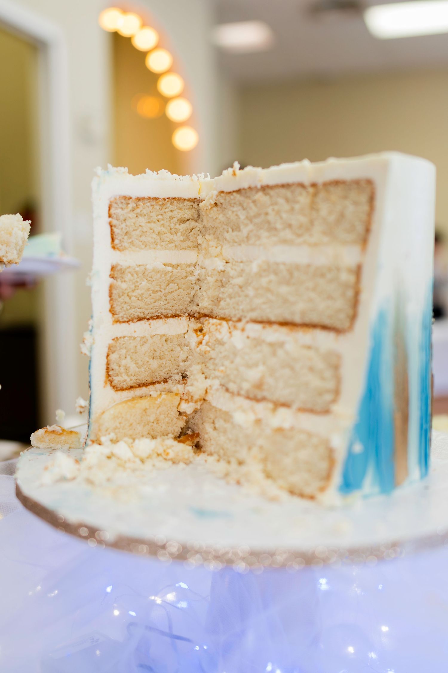 Close-up view of a sliced white layer cake showing multiple tiers of vanilla cake with cream frosting.