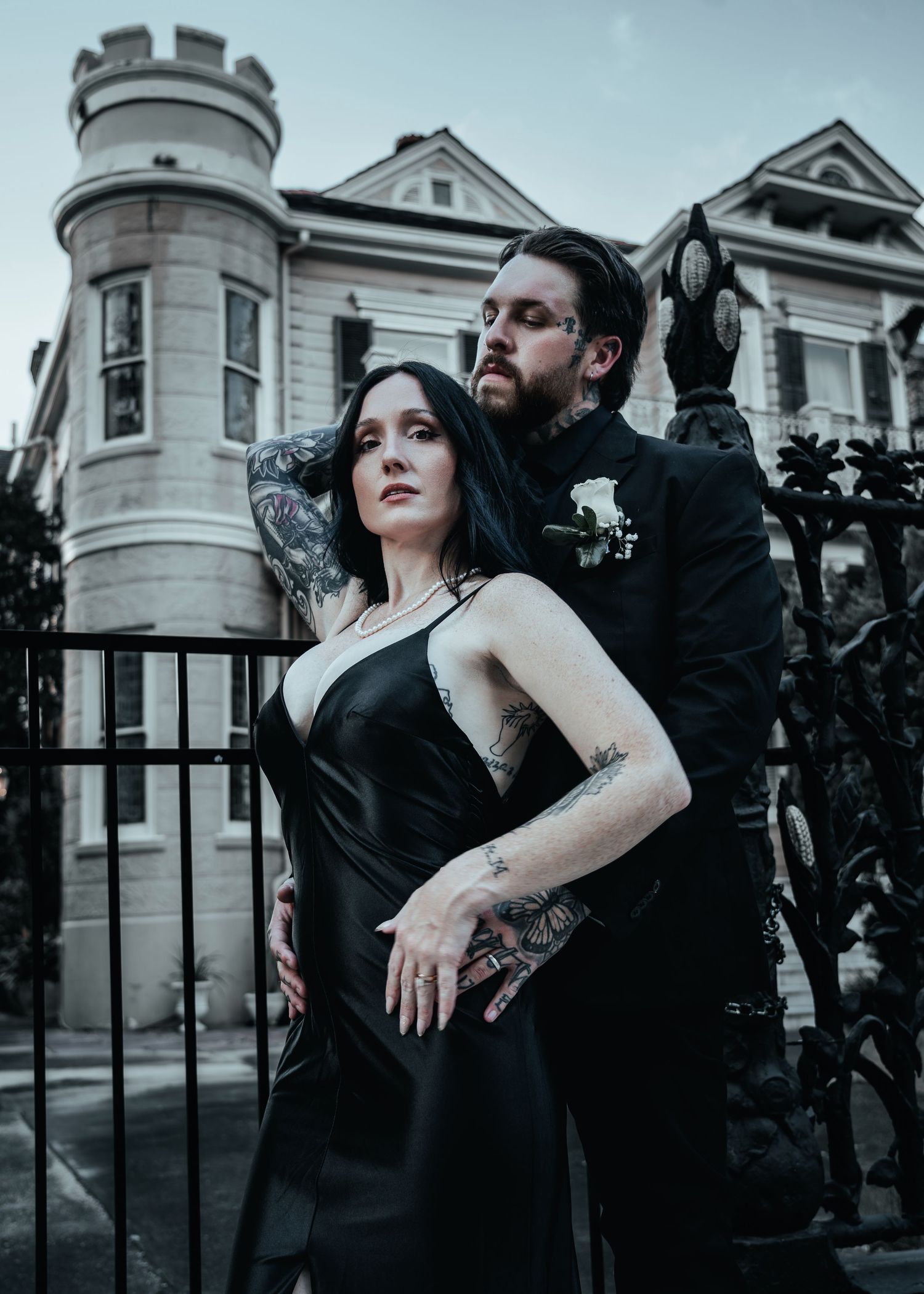 Artistic black and white photo series of a couple in dramatic poses outside a Victorian mansion with iron gates.