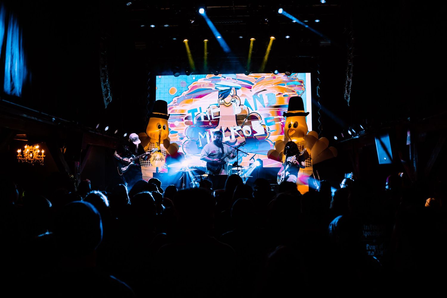 Nightclub concert scene with illuminated digital screen and crowd in dark atmosphere.