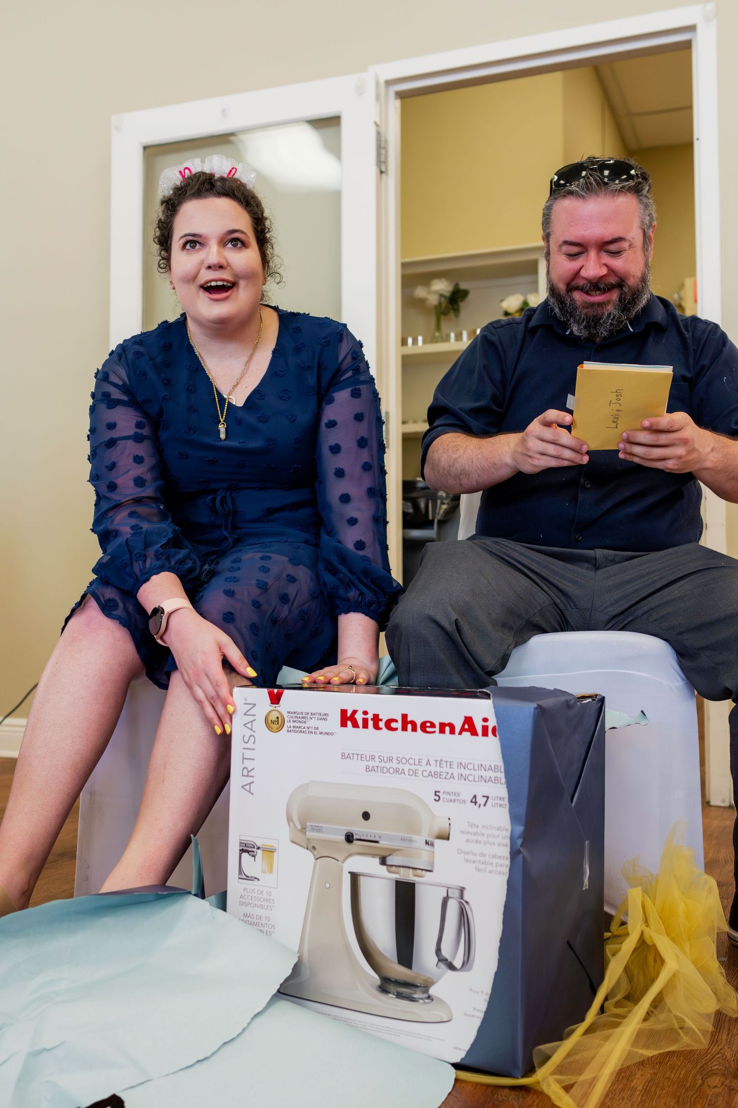 Opening gifts at a celebration with a KitchenAid mixer box visible.