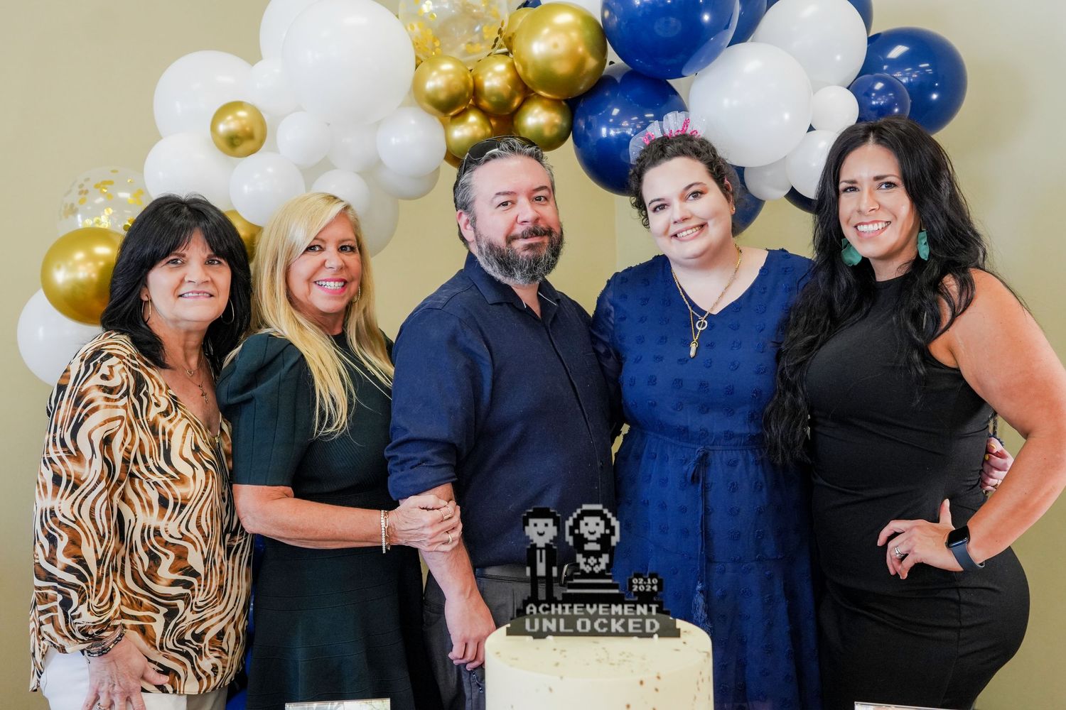 A special occasion with a beautifully decorated cake and balloon arch in navy blue, white, and gold colors.