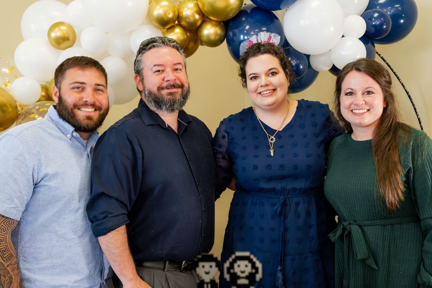 Celebration gathering with gold and navy balloon decorations in background.