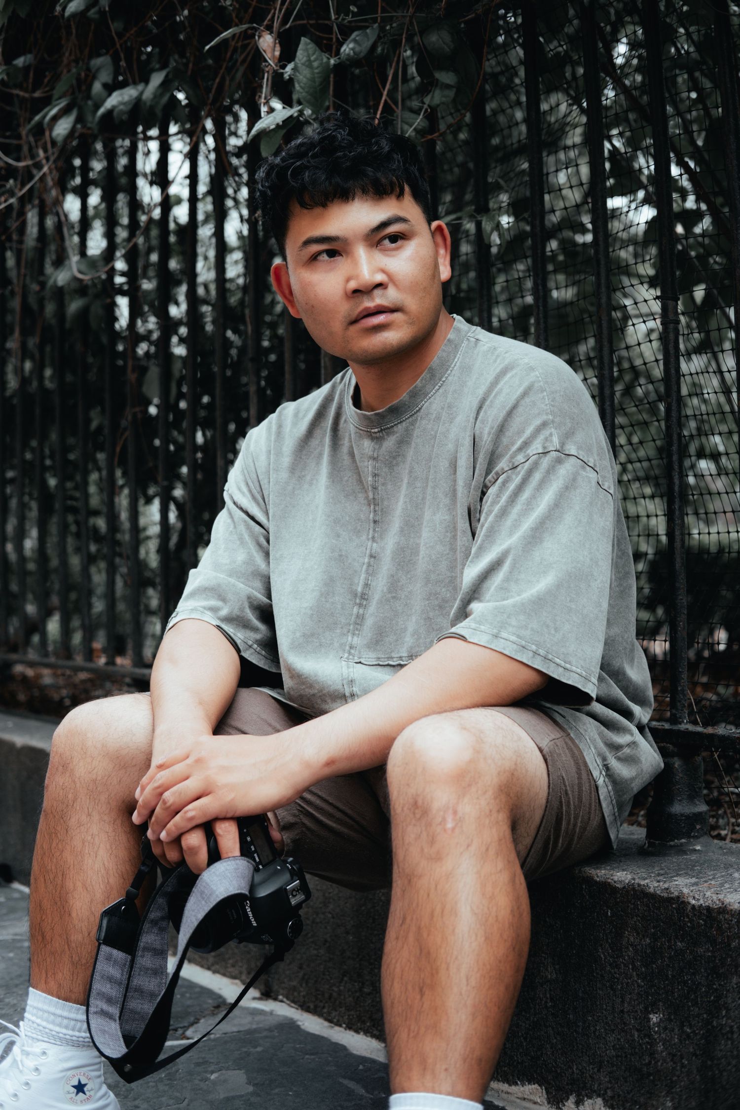 Person in grey outfit seated on concrete steps with trees in background.