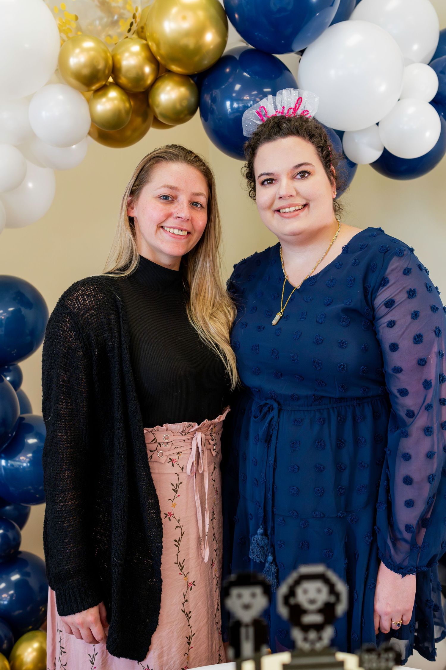 A celebratory event with navy blue and gold balloon decorations and a festive cake display.