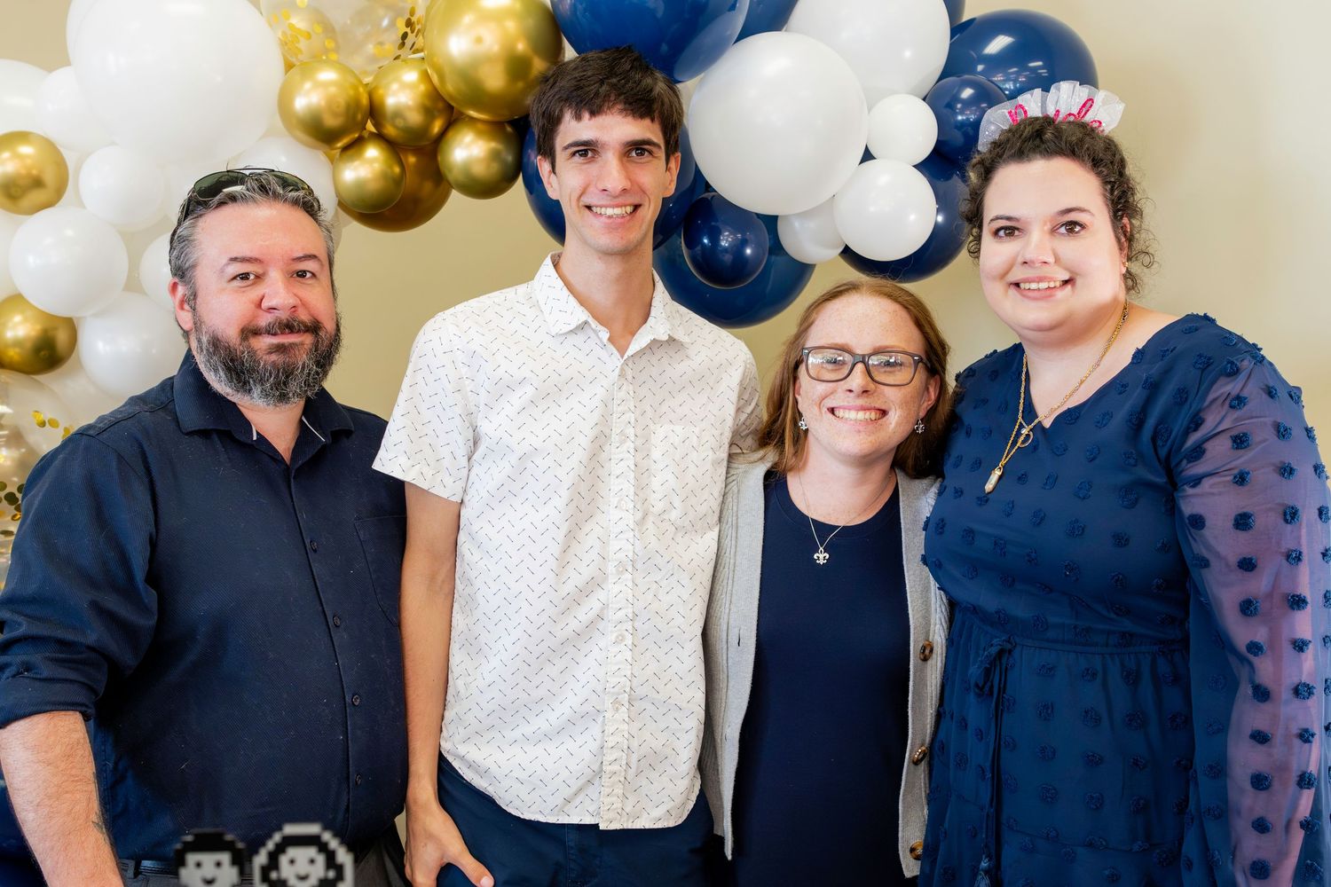 A party celebration with balloon decorations featuring gold, white, and navy blue colors.