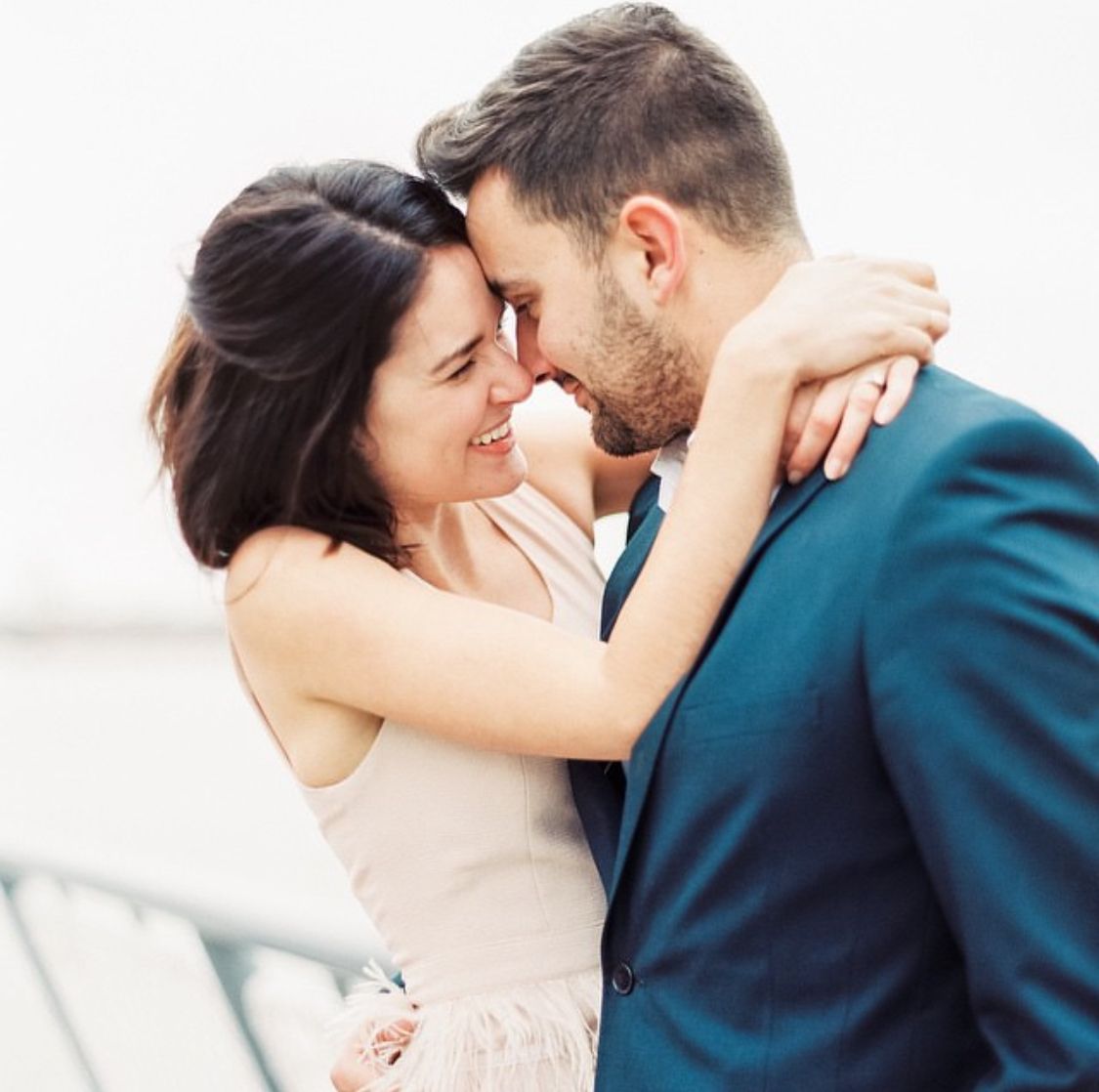 Romantic wedding couple embracing in soft natural light during intimate outdoor portrait session.