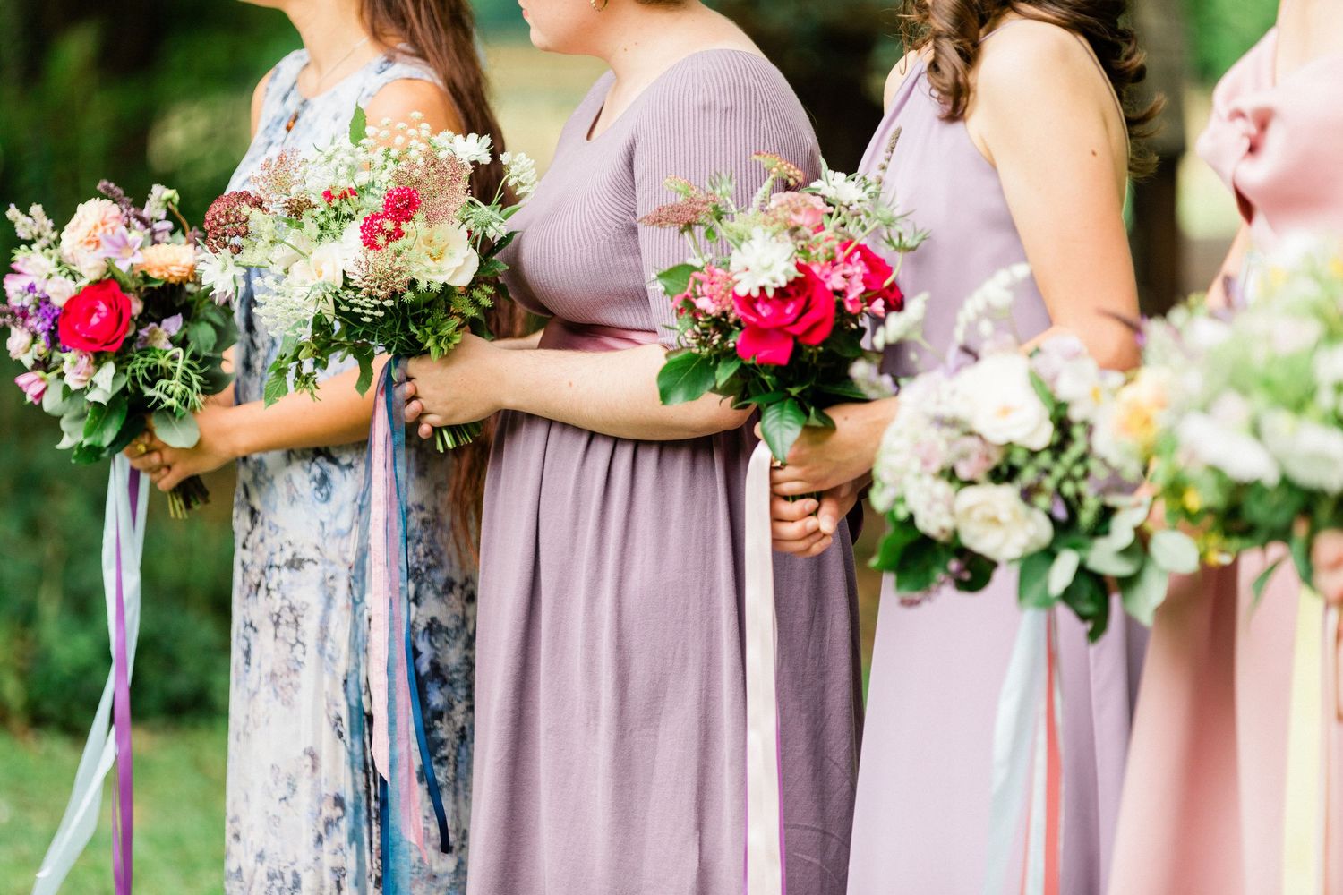 Bridesmaids holding seasonal flower bouquets during outdoor wedding ceremony