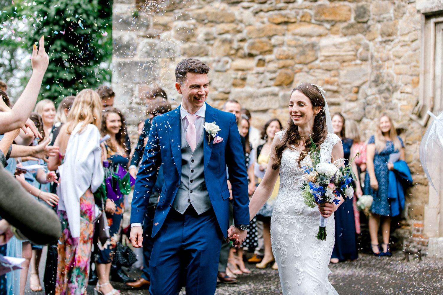Confetti shot of bride and groom walking through guests following a church ceremony in Edenbridge, Kent