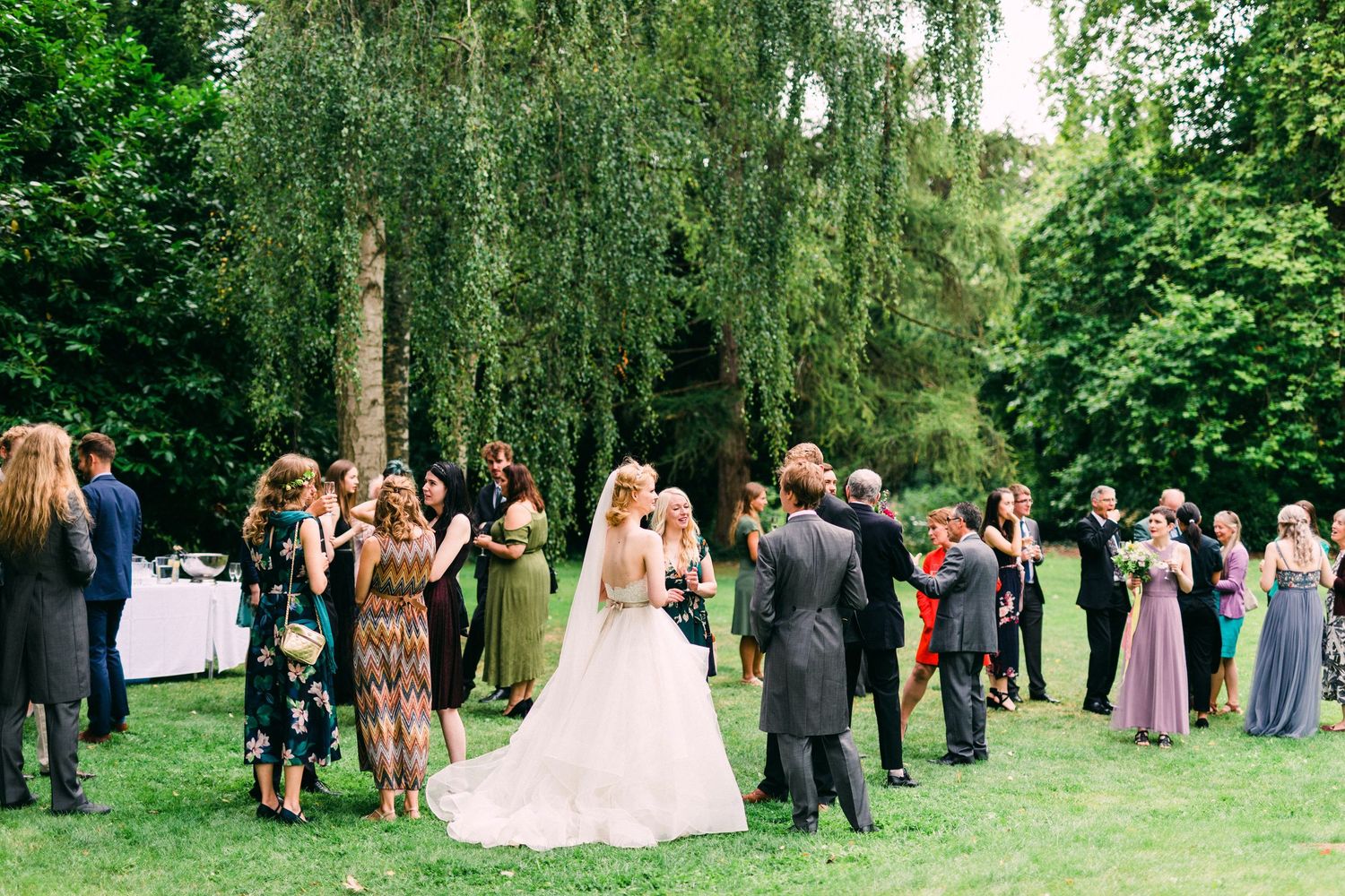 Newlyweds laughing with friends in garden drinks reception in wedding venue in France