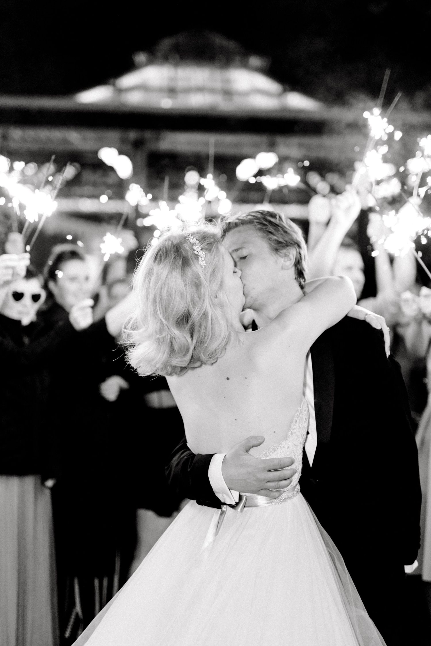 Newlyweds kissing under sparklers surrounded by cheering guests Hallines France