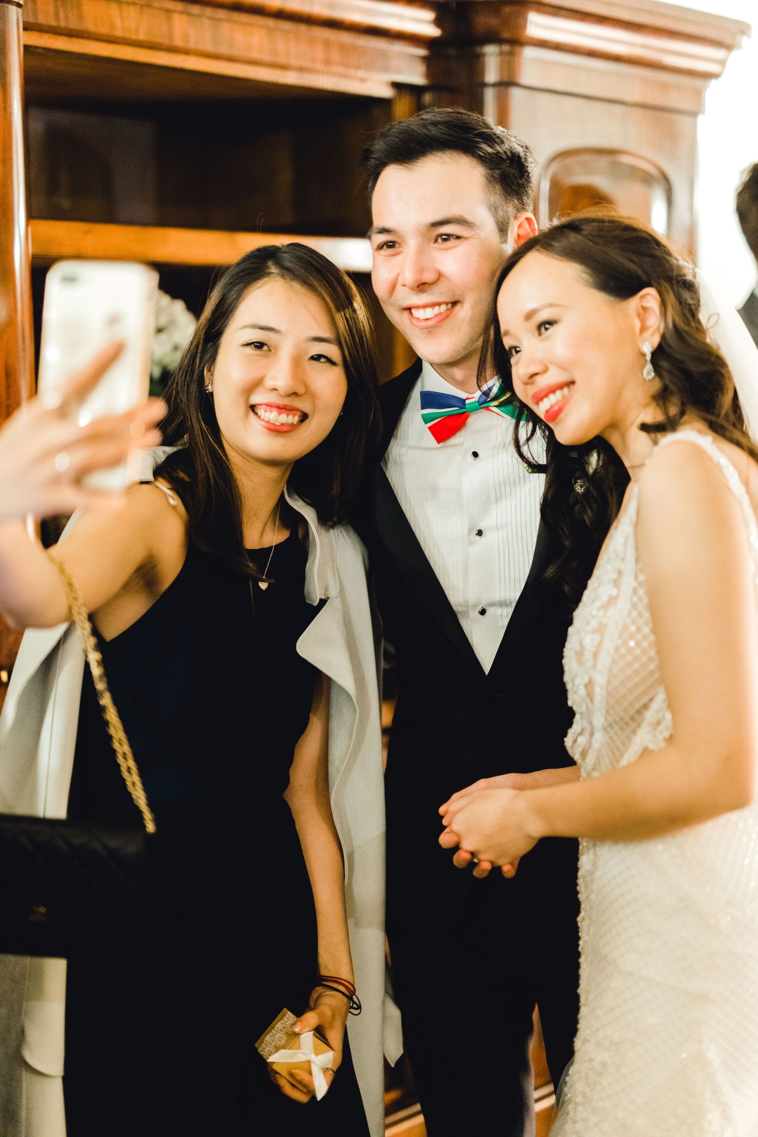 Bride and groom taking selfies with guest – romantic evening wedding Gosfield Hall Essex - candid wedding photography