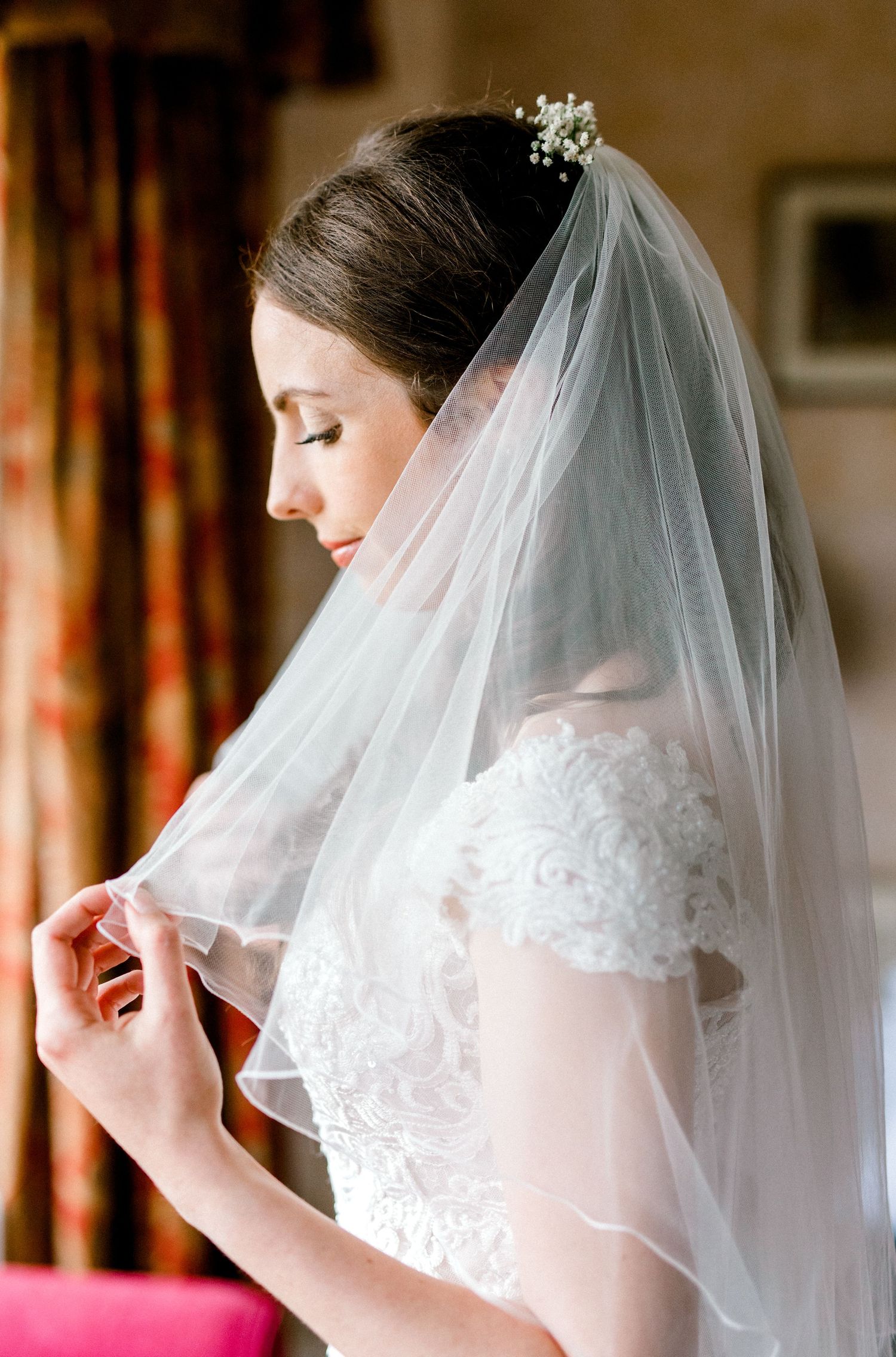 Final touches before the ceremony — bride adjusting veil in mirror in Hoath House, Kent wedding