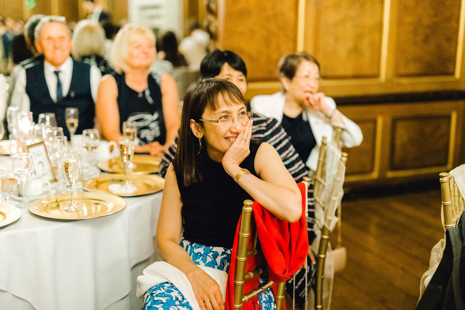 Guests smiling and laughing as the groom gives a funny toast – candid wedding speech photo Gosfield Hall Essex - candid wedding photography