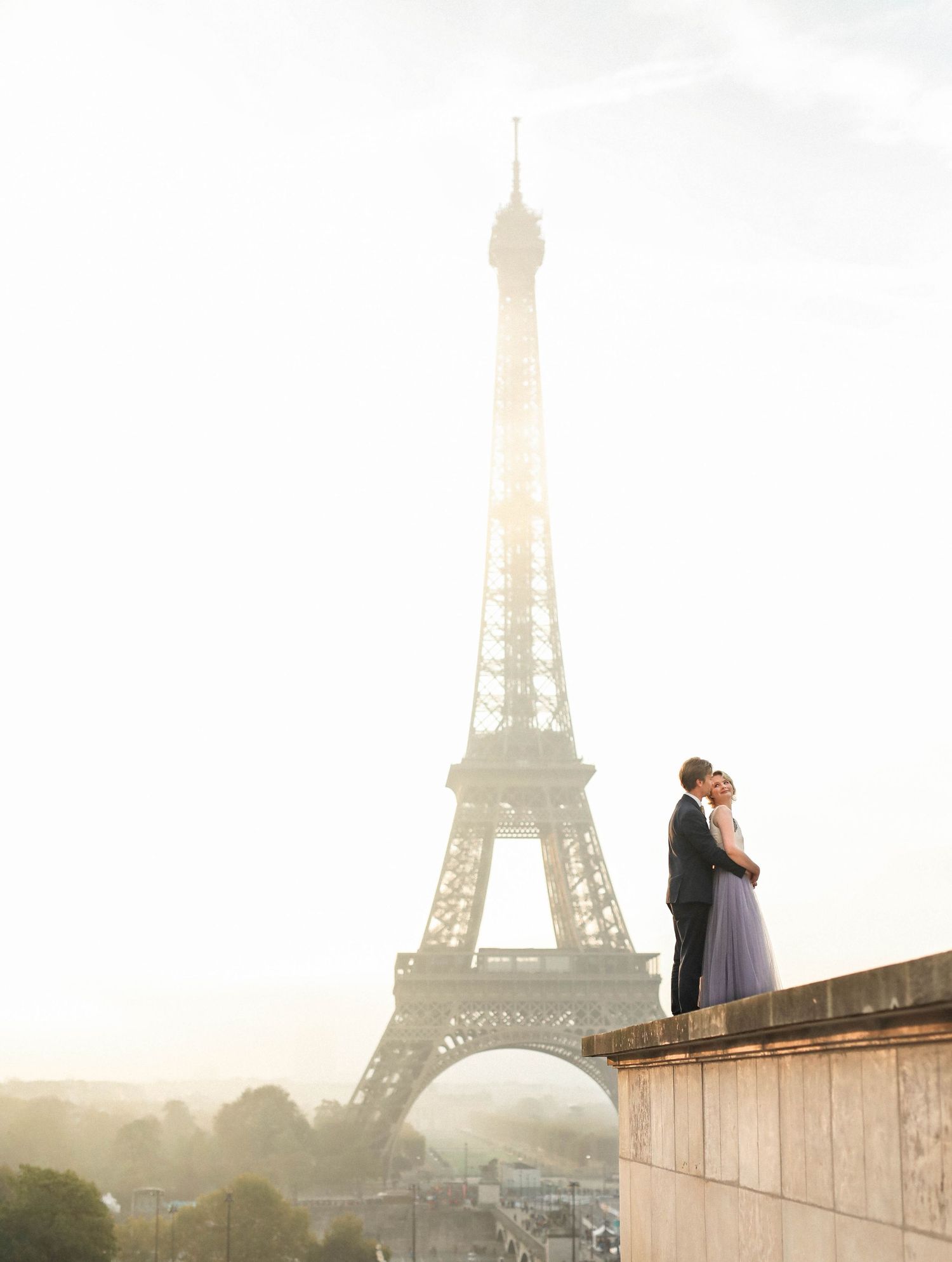 Bride-to-be and groom embracing in sunrise golden light during professional engagement shoot in Paris France