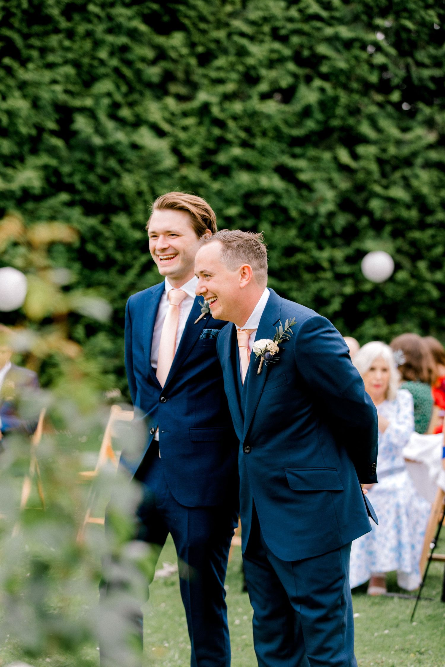 Candid moment of groom and best man sharing a joke during London wedding ceremony