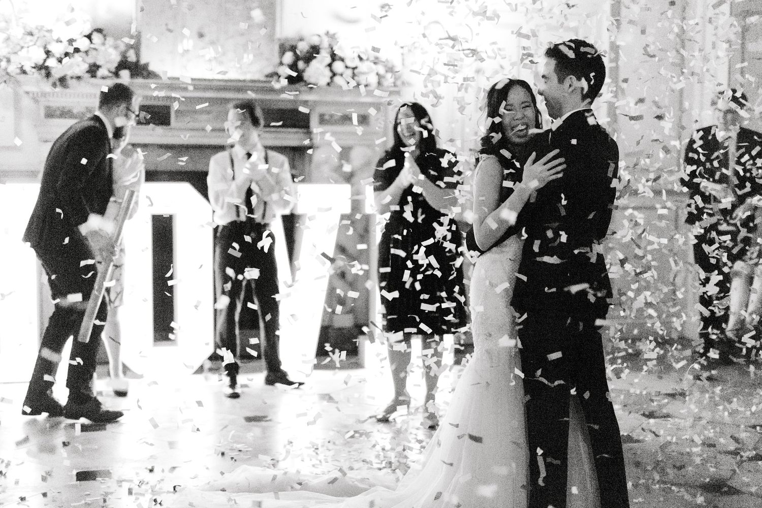 Confetti floating through the air as the bride and groom hug – fun, candid wedding Gosfield Hall Essex - candid wedding photography