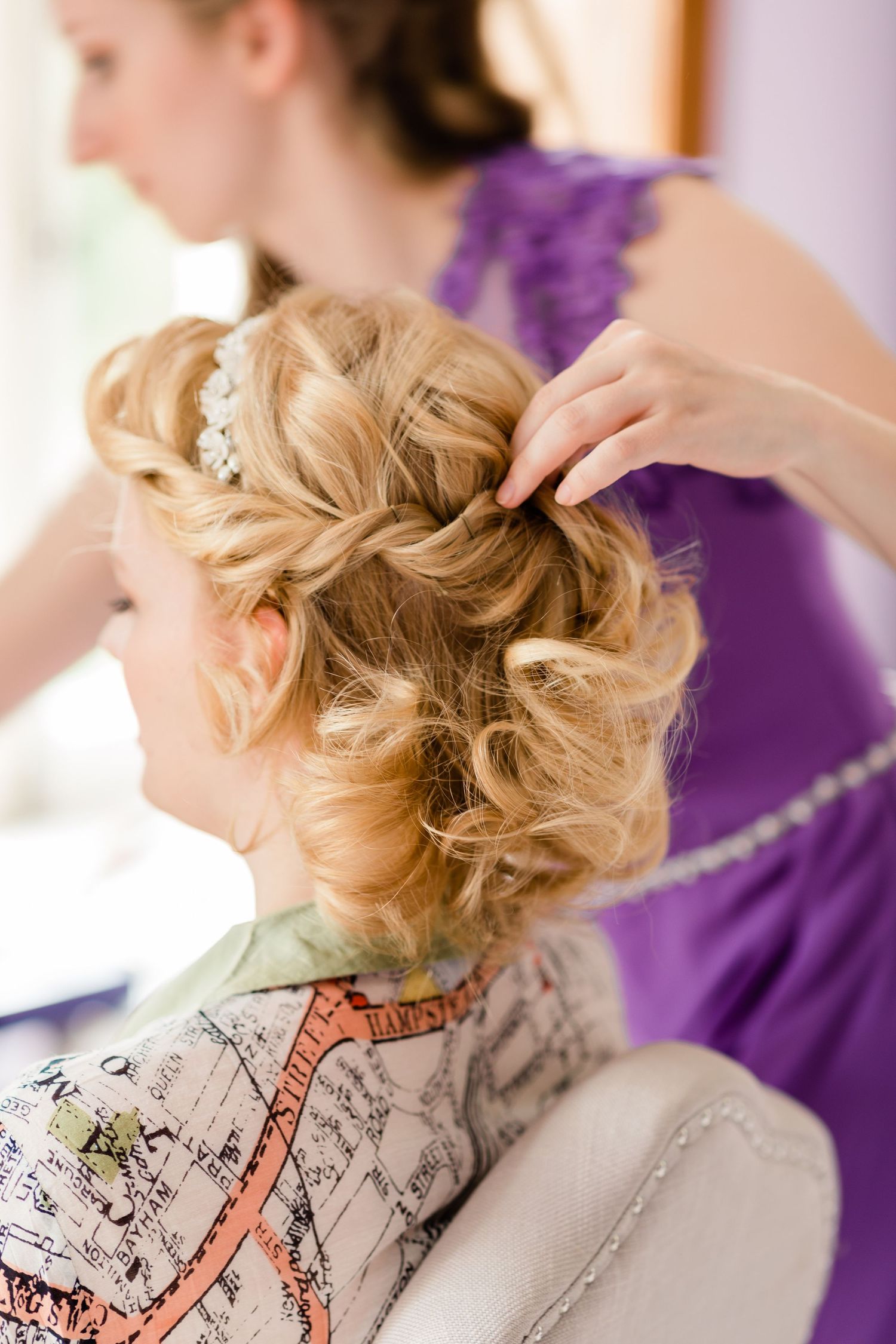 Bride’s hair in progress with soft waves and natural light in prep room