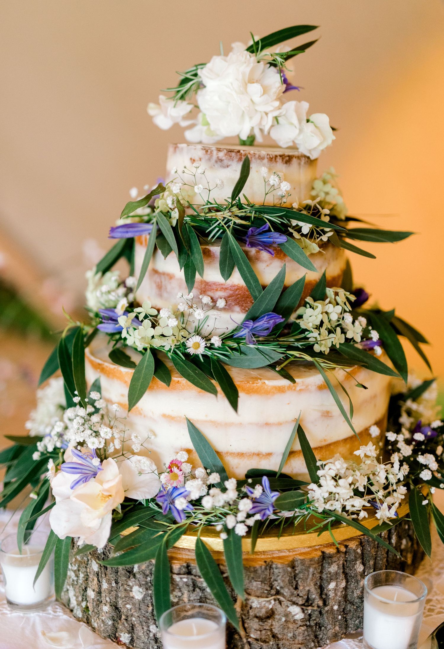 Rustic wedding cake with naked frosting and wildflower decorations at Kent venue