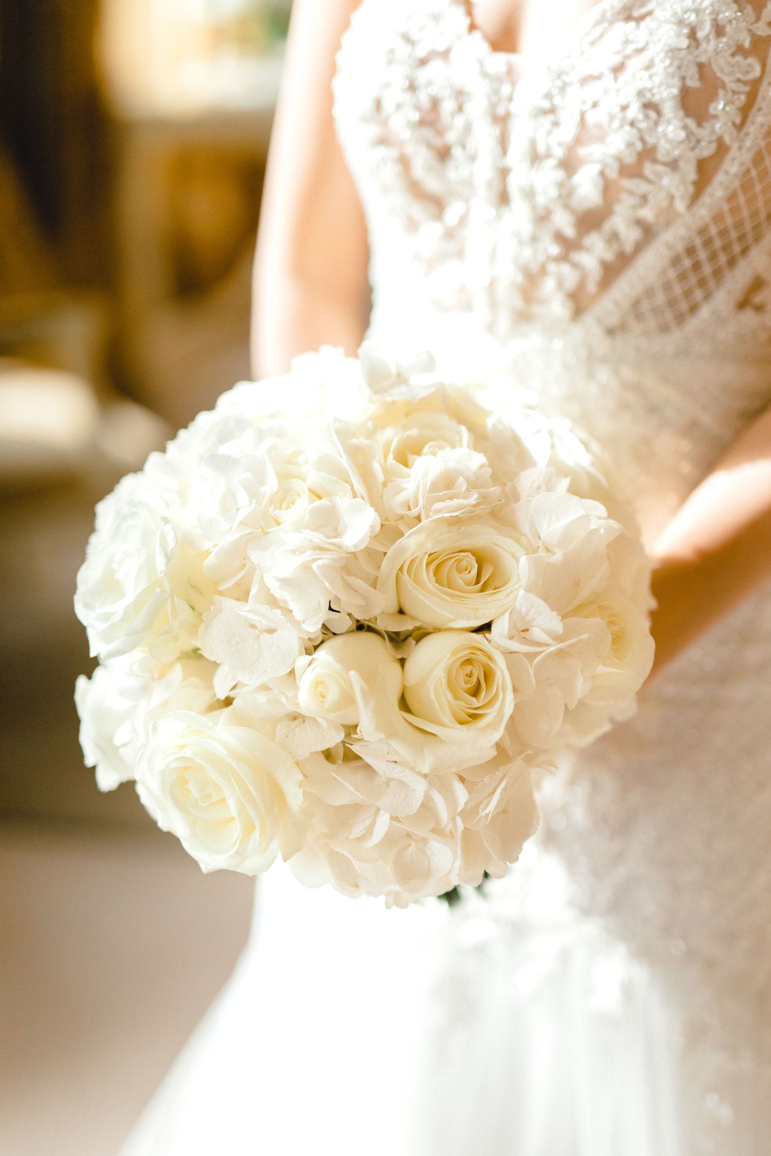 Bride holding white rose bouquet with soft window light photography in Essex