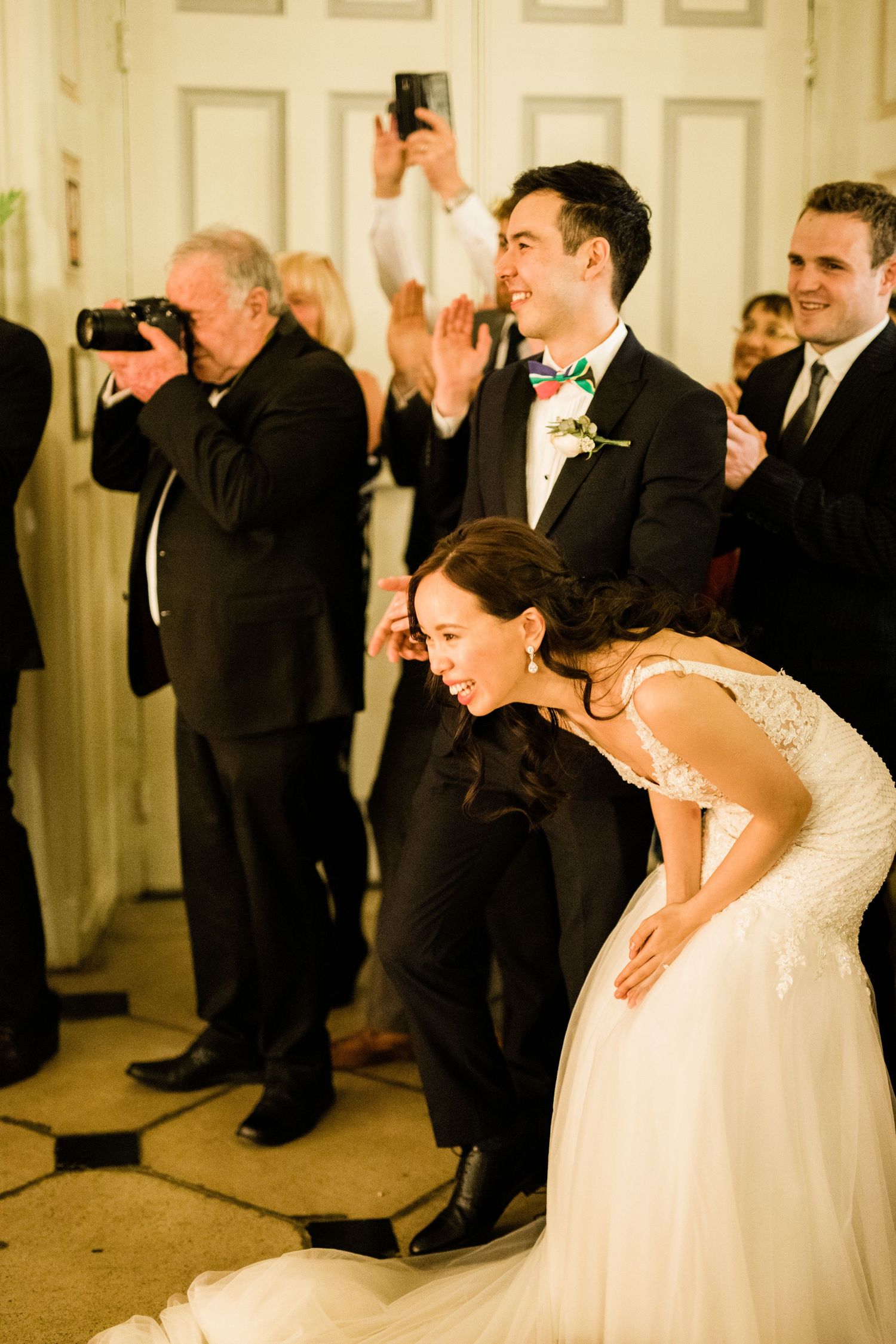 Bride and groom laughing in shock as wedding guests perform a surprise dance – Gosfield Hall Essex - candid wedding photography