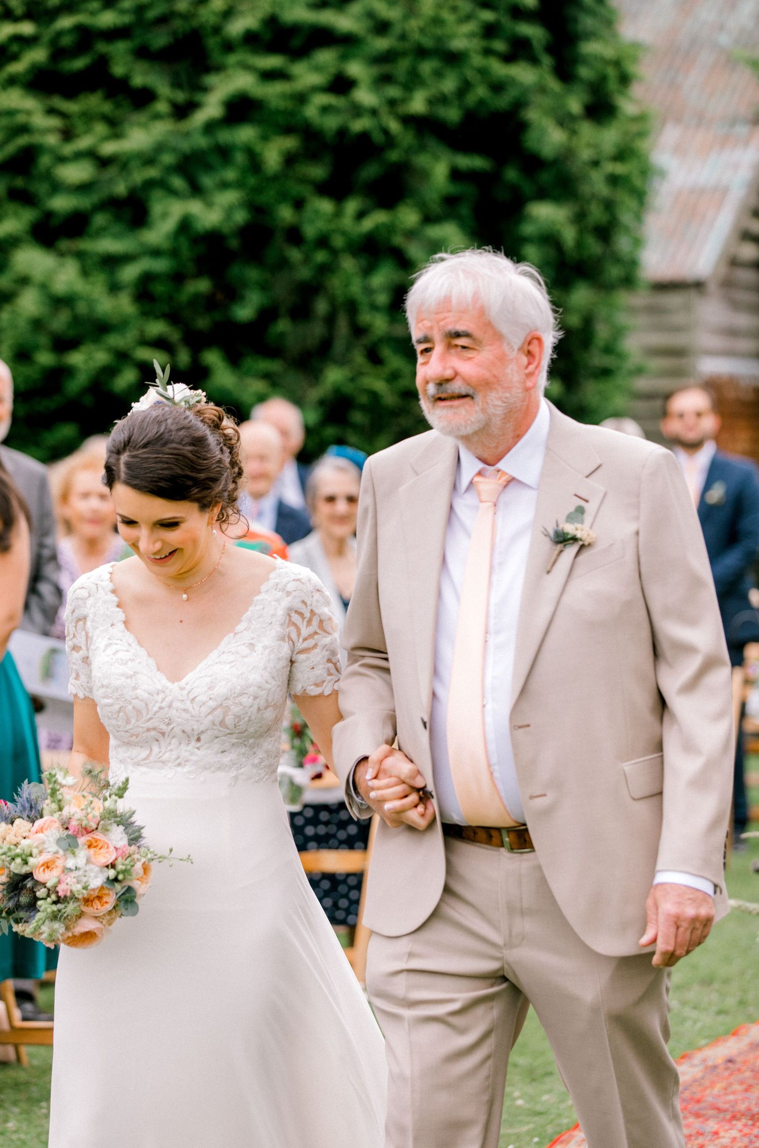 Bride holding her father’s arm while walking down the aisle at outdoor summer wedding London