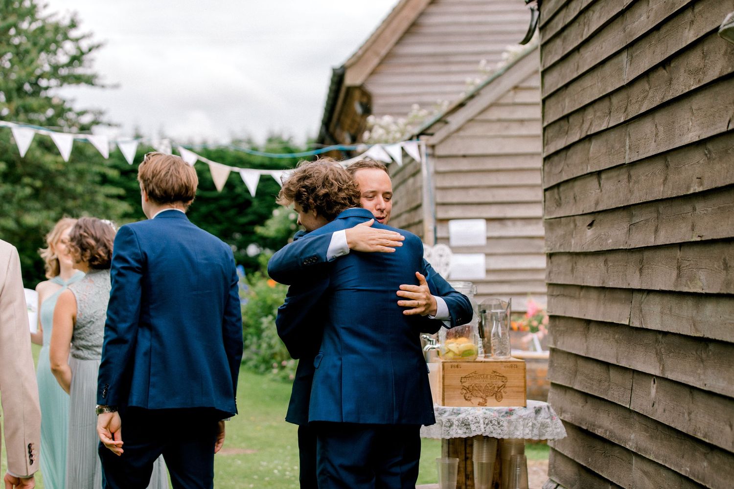 Groom and friends celebrating with hugs at elegant summer wedding in London