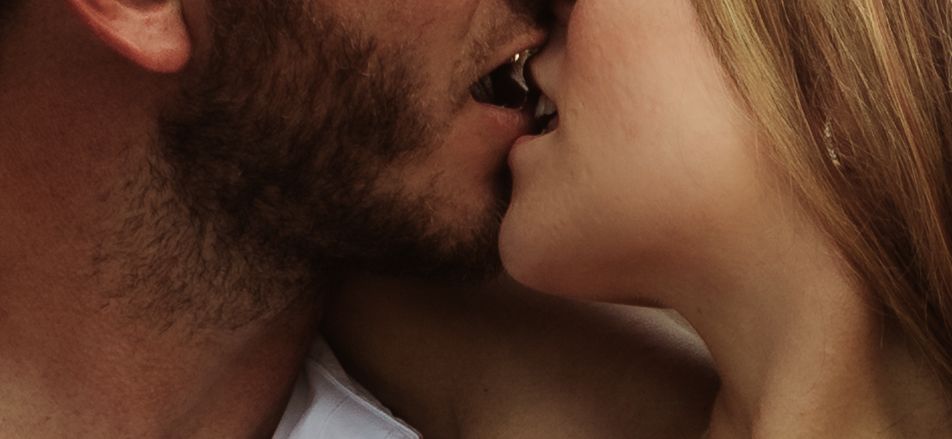 Close-up of a romantic couple sharing a tender kiss, with soft natural lighting highlighting their faces.