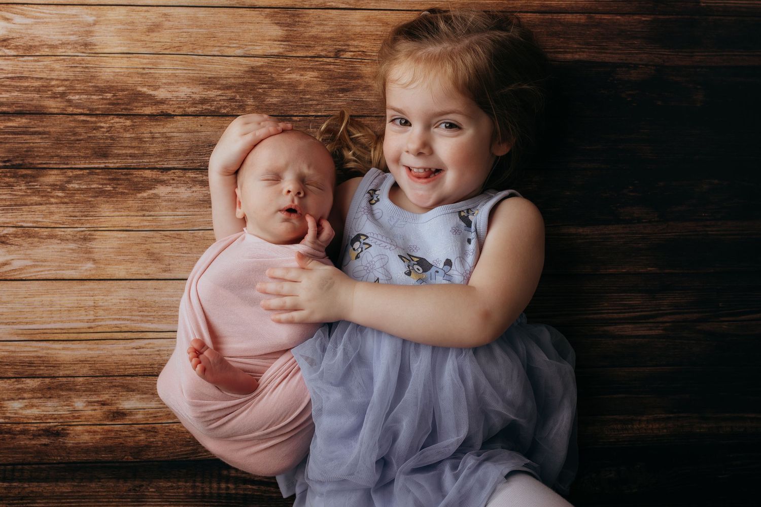 A series of tender moments between siblings with a baby against a rustic wooden wall background.