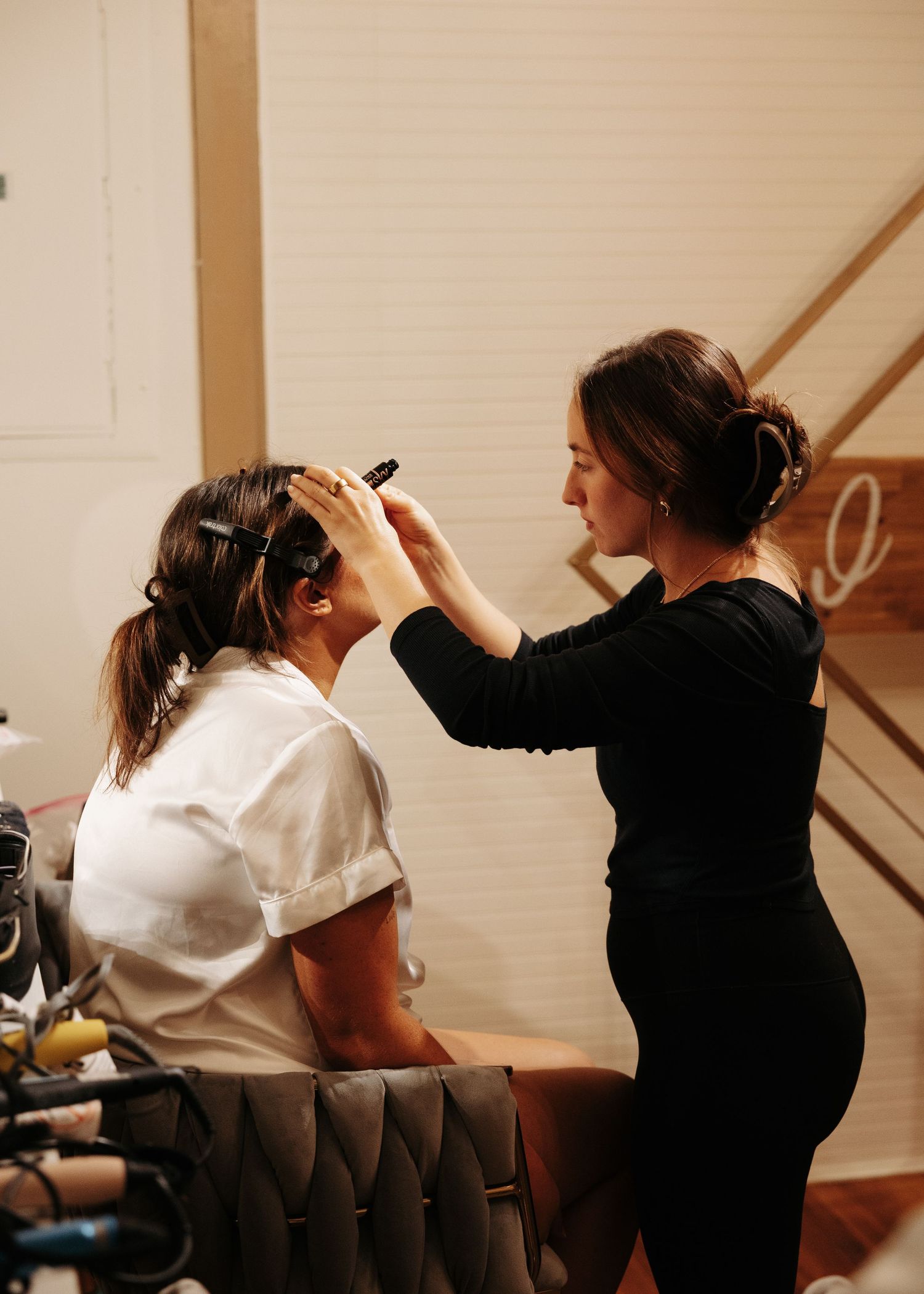 Makeup artist applying finishing touches to bride's hair and makeup before wedding ceremony.