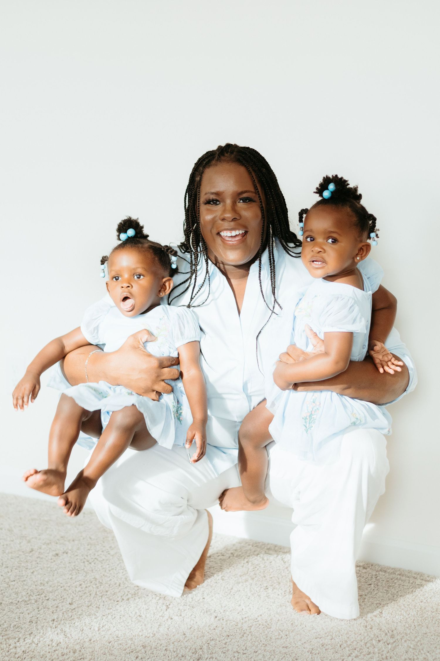 Playful family photoshoot with matching white outfits against a bright white background.