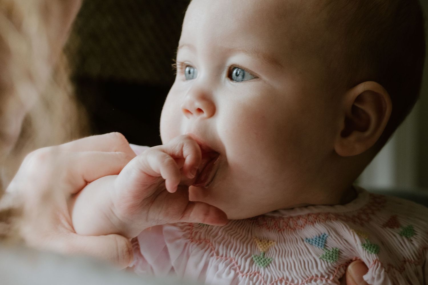 Close-up portrait of a baby with bright blue eyes and rosy cheeks.