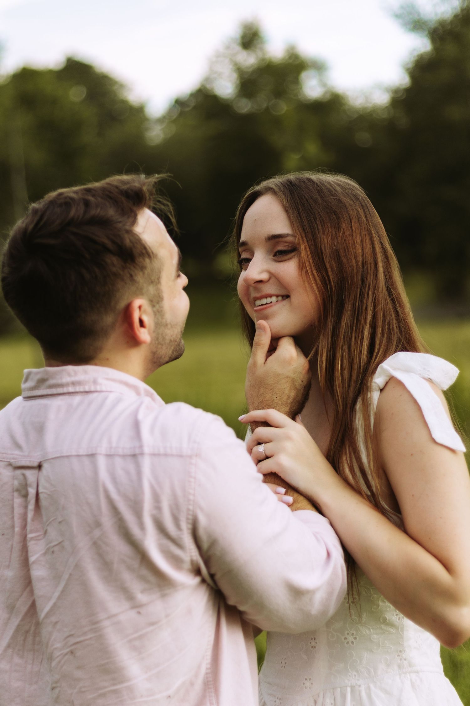 A romantic couple shares an intimate moment outdoors against a blurred natural background.