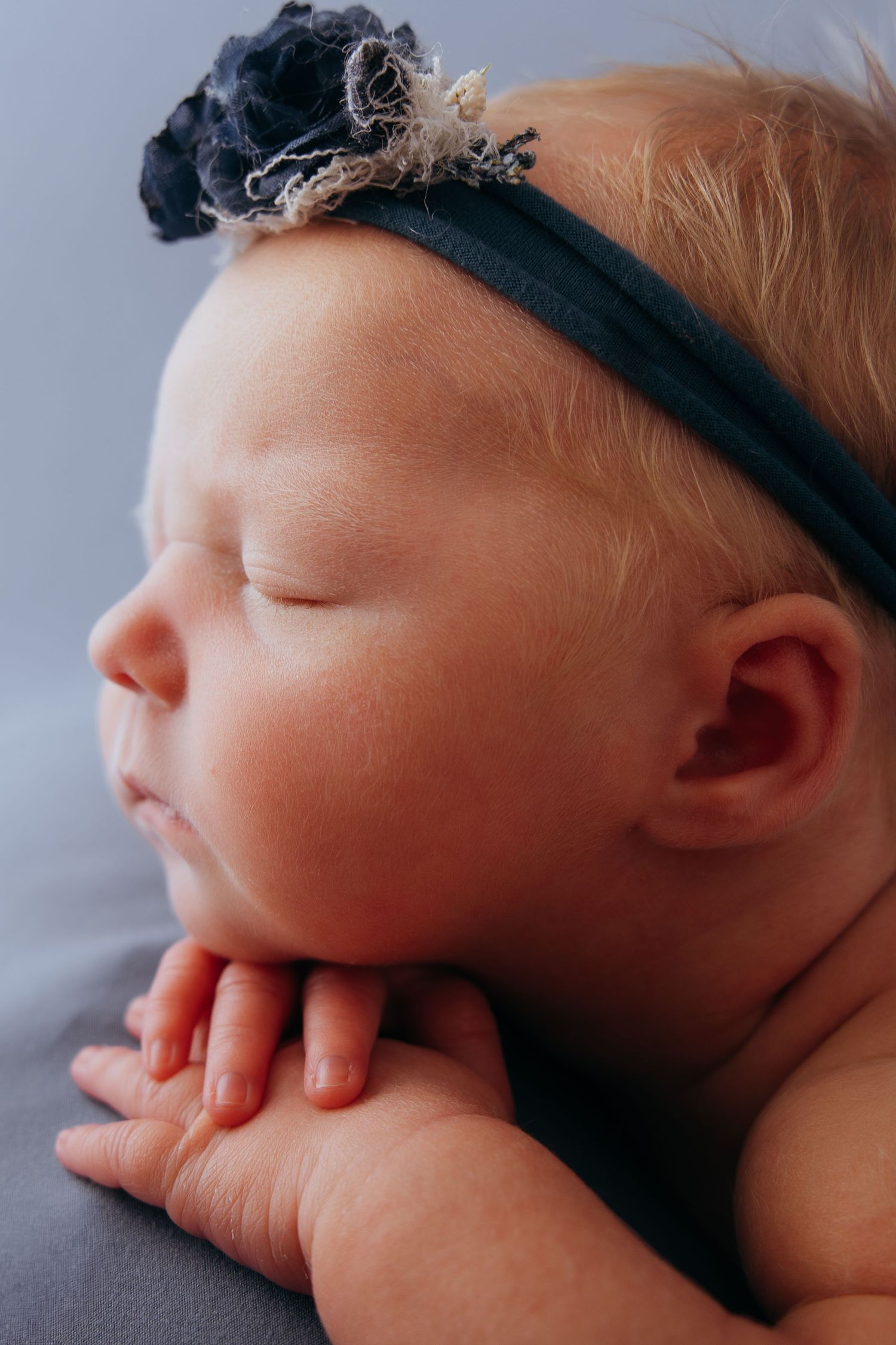 Close-up series of a sleeping baby wearing a black headband in various angles against a light gray background.